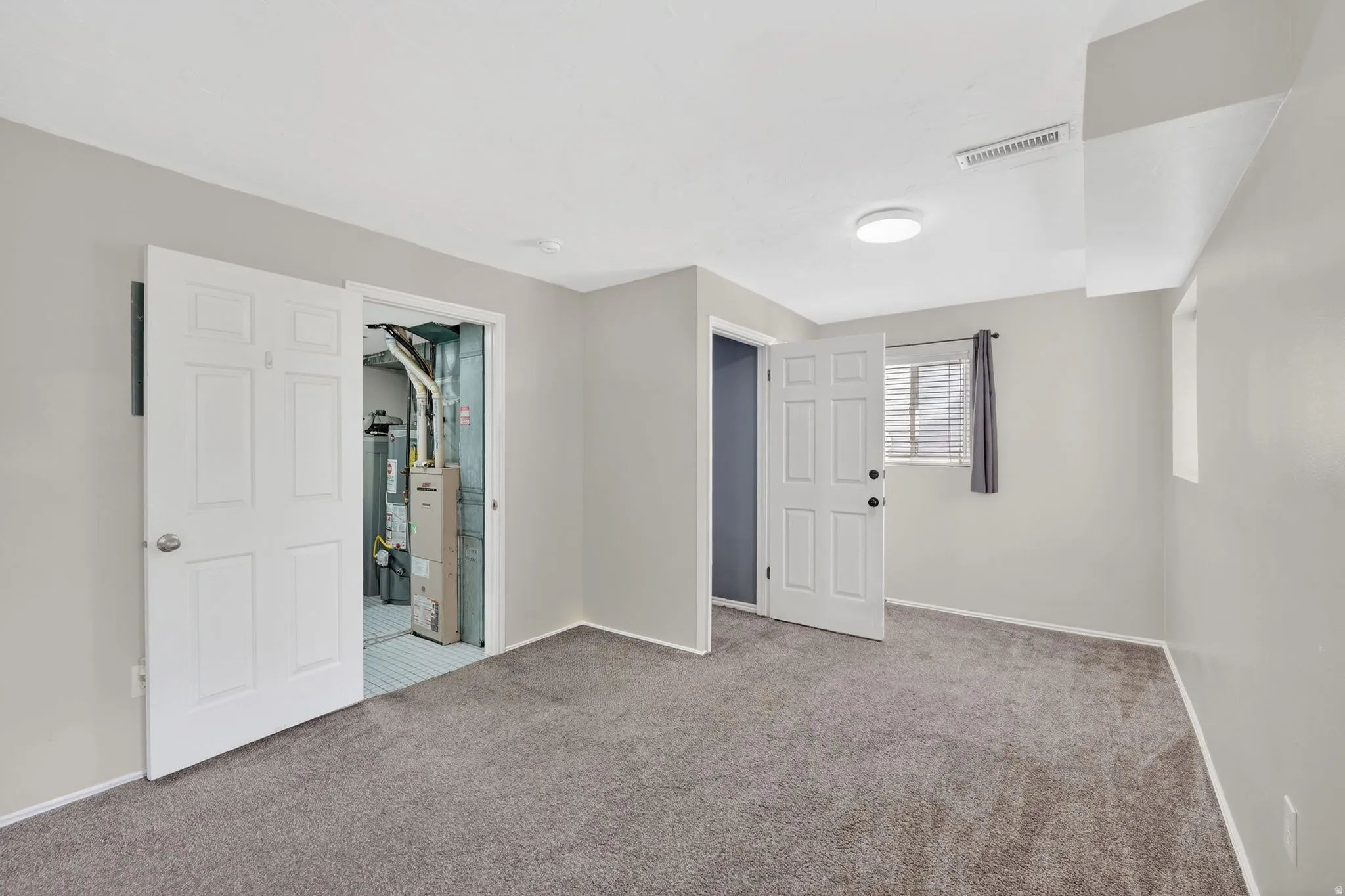 Unfurnished bedroom with carpet flooring, water heater, and ensuite bathroom