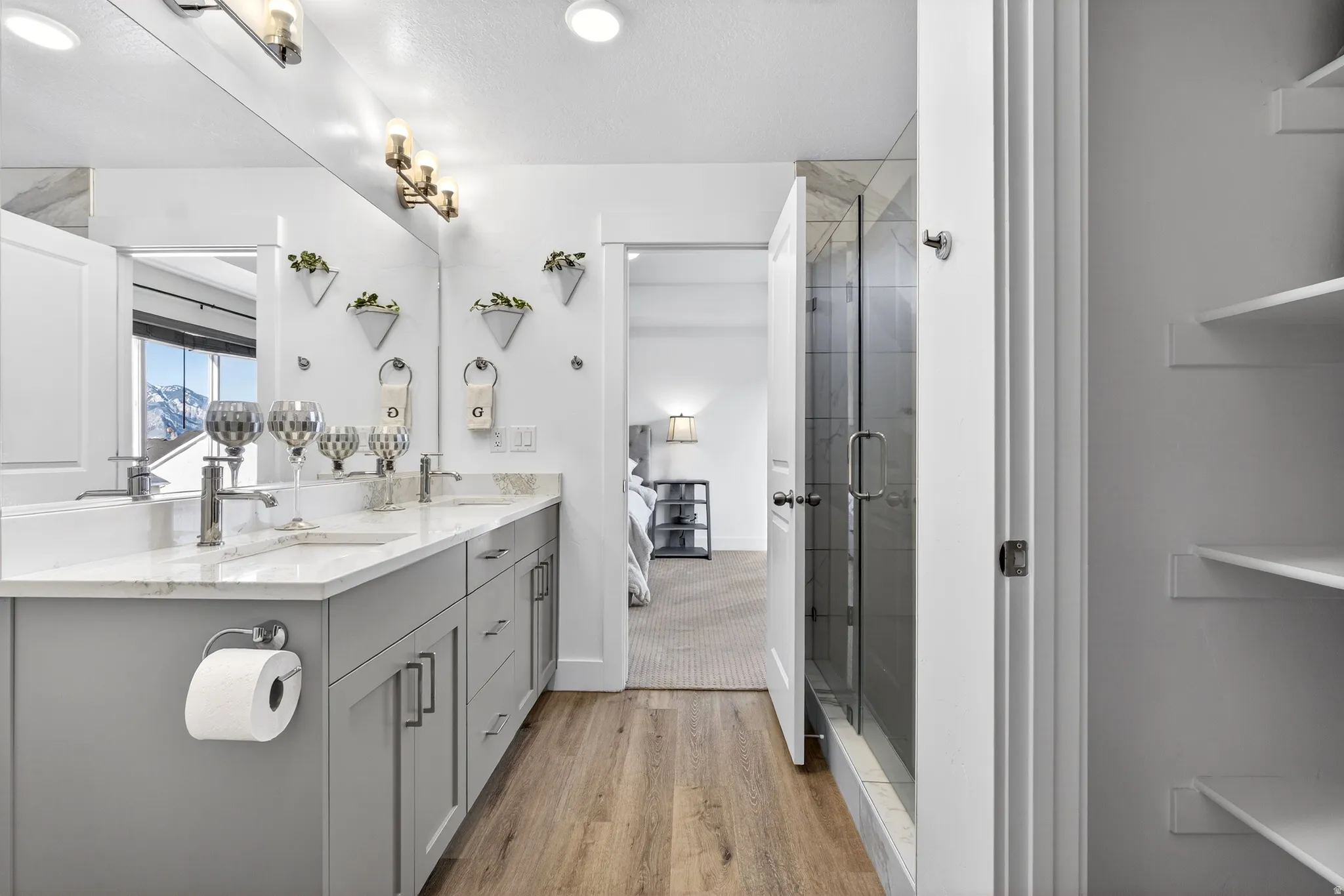 primary bedroom ensuite bathroom with double vanity, light finished floors, glass shower, linen closet, and walk in coset