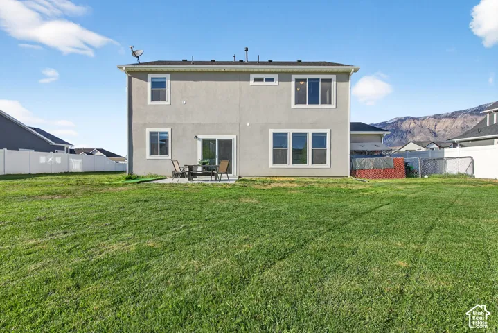 Rear view of property with a patio, a partially fenced backyard, and a mountain view