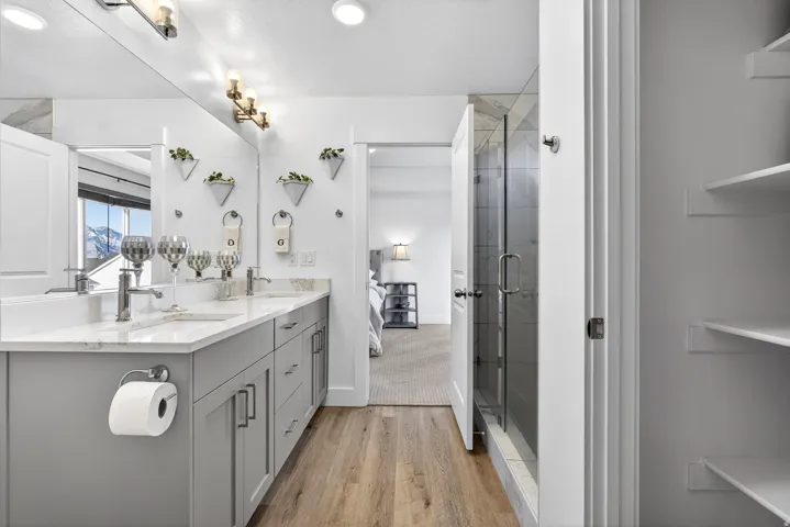 primary bedroom ensuite bathroom with double vanity, light finished floors, glass shower, linen closet, and walk in coset