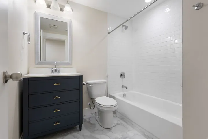 Bathroom featuring vanity,  shower combination, and light marble finish flooring
