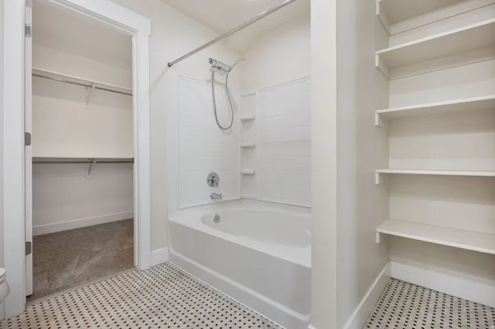Bathroom featuring a walk in closet and tub / shower combination