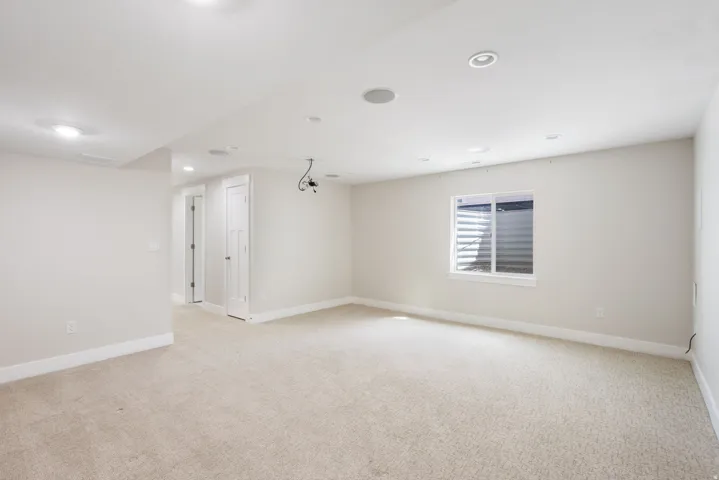 Empty room featuring light colored carpet, recessed lighting and projector.
