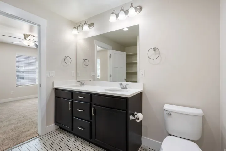 Full bath featuring double vanity, a ceiling fan, healthy amount of natural light, and light carpet