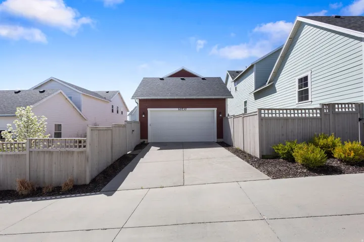 View of side of home with a garage, driveway, and a shingled roof
