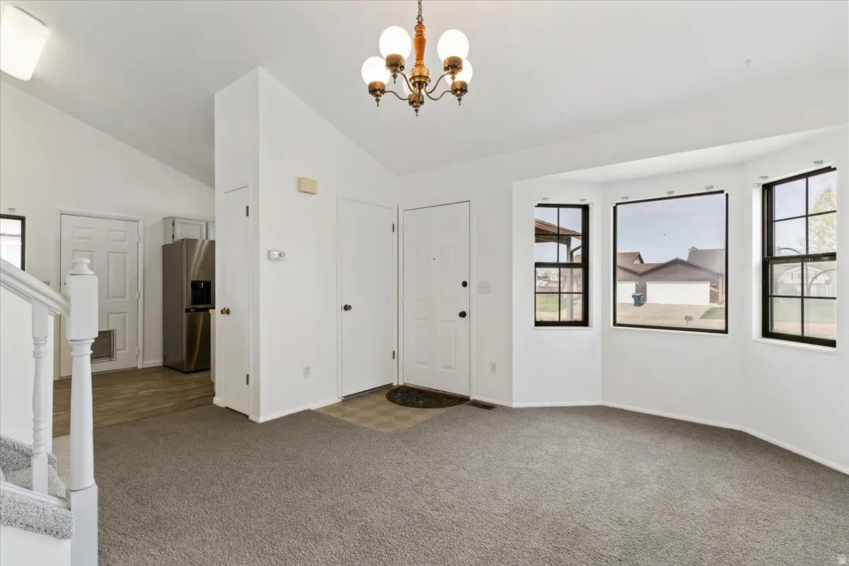 Carpeted foyer entrance with a chandelier and vaulted ceiling