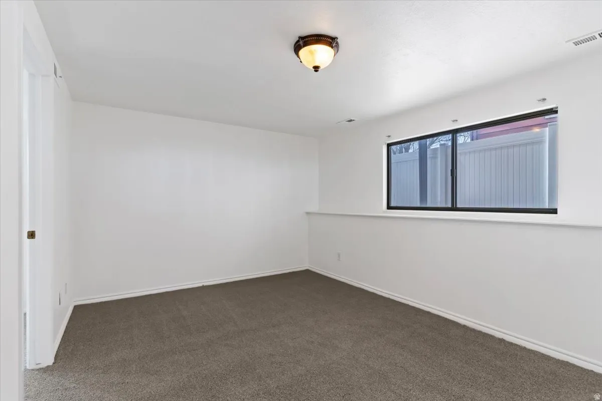 Empty room featuring dark carpet and baseboards