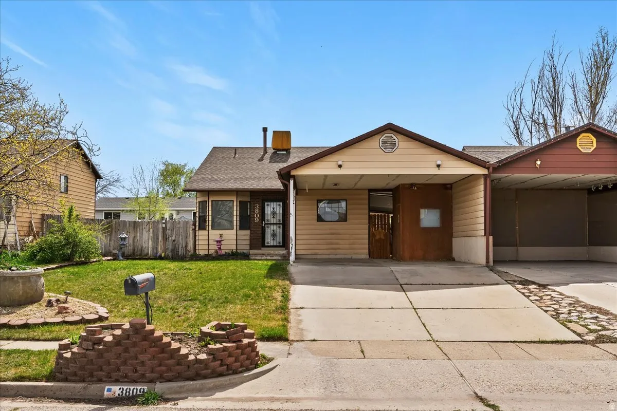 View of front of home with roof with shingles, an attached carport, and driveway