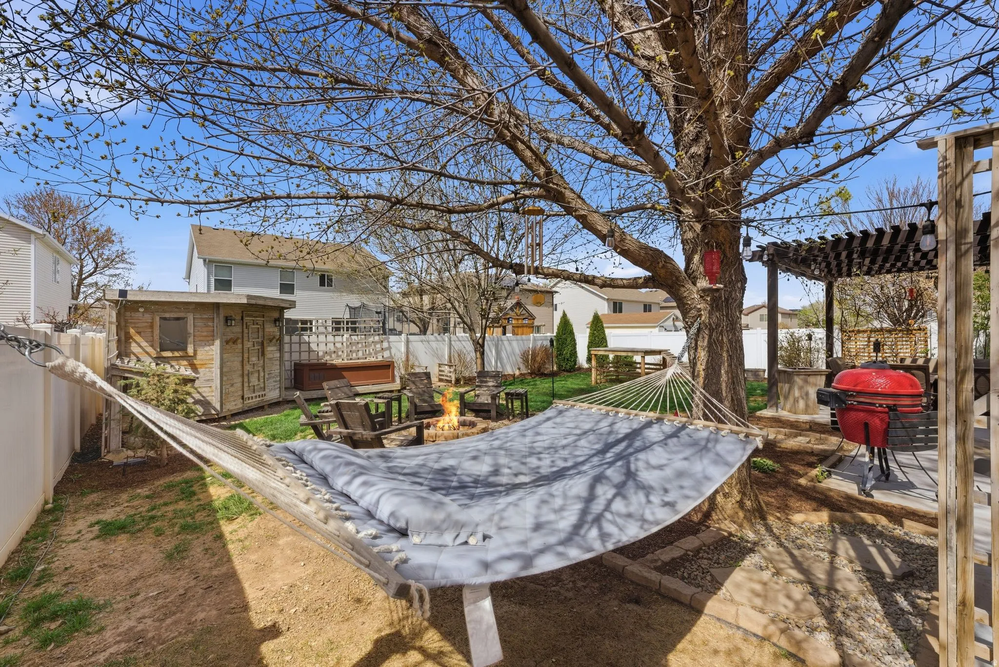 Fenced backyard featuring a patio, a fire pit, a pergola, a residential view, and a shed