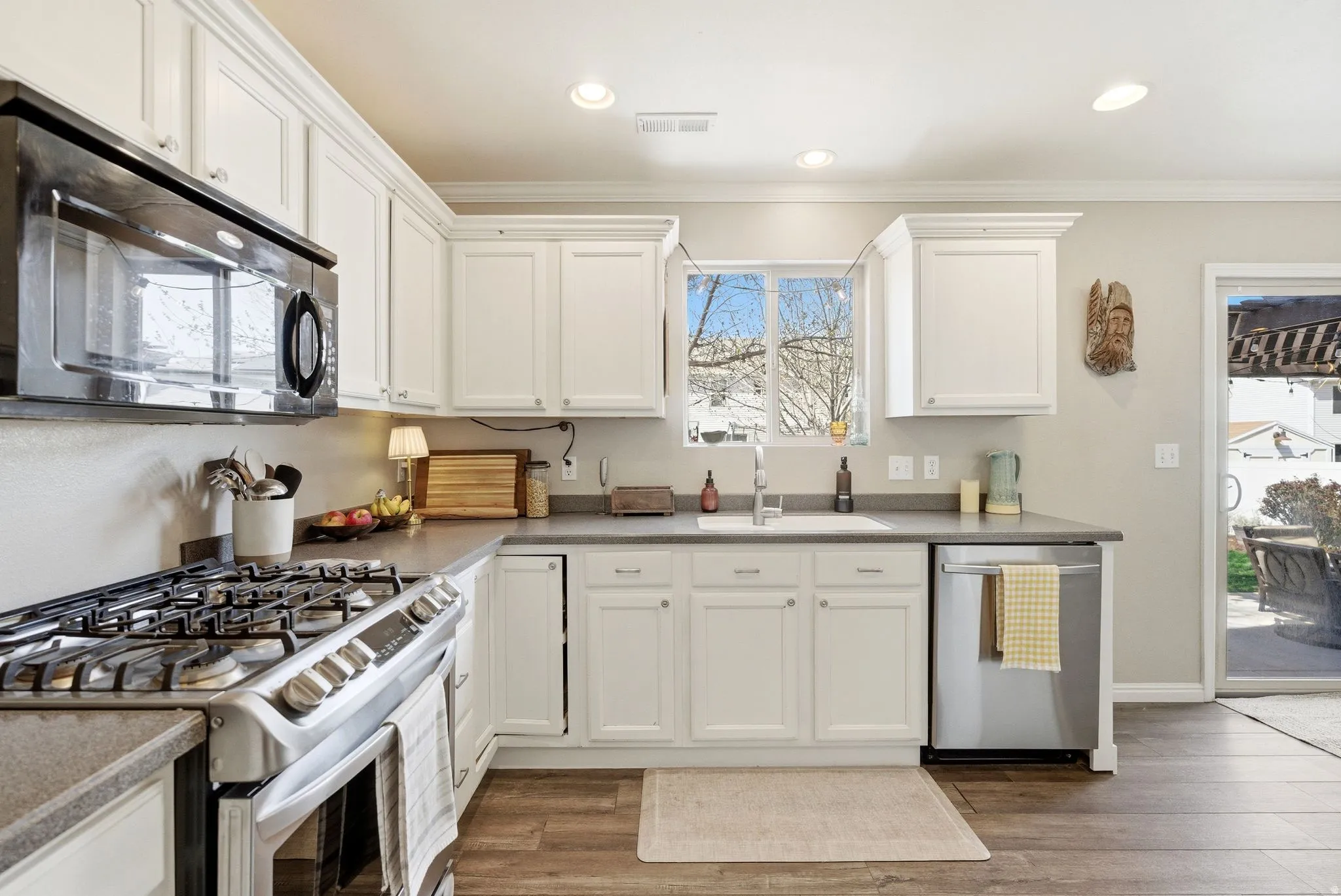 Kitchen featuring stainless steel appliances, white cabinetry, ornamental molding, healthy amount of natural light, and light wood-type flooring