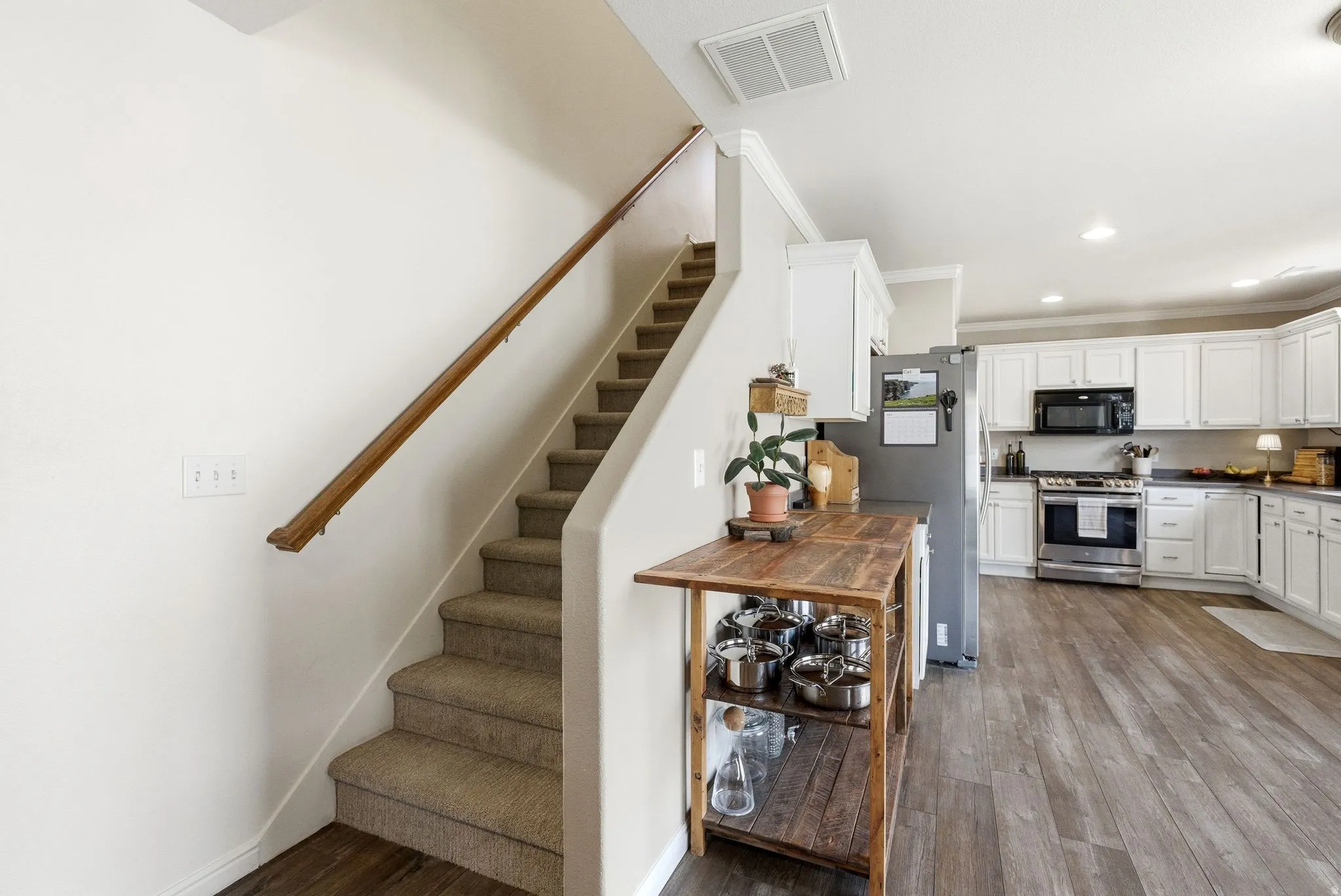 Staircase with wood finished floors, recessed lighting, and crown molding