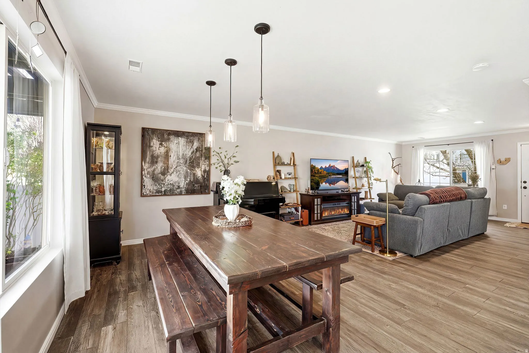 Dining space featuring wood-type flooring, ornamental molding, and a lit fireplace