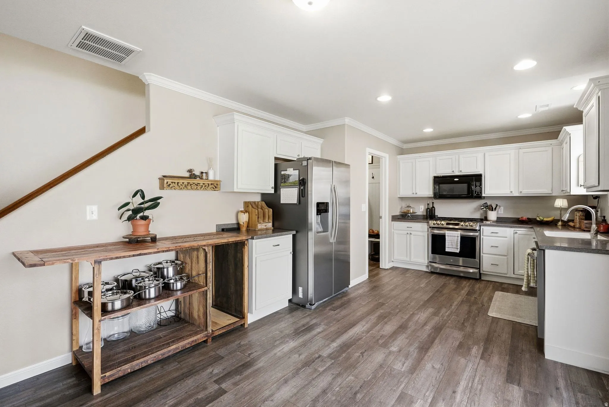 Kitchen featuring dark countertops, stainless steel appliances, white cabinets, ornamental molding, and recessed lighting