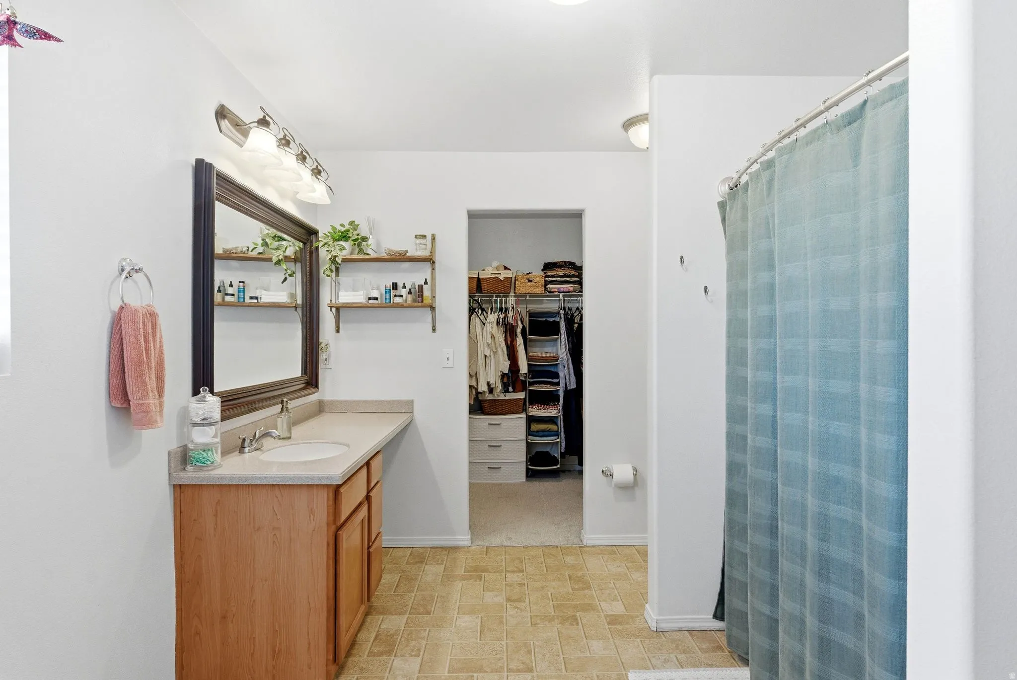Full bath featuring vanity, curtained shower, and a spacious closet