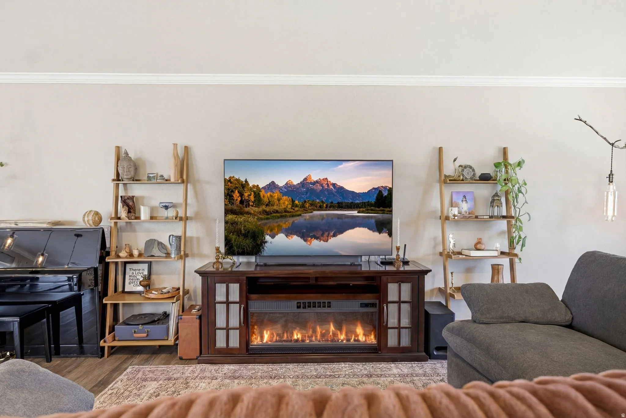 Living room with a glass covered fireplace, wood finished floors, and crown molding