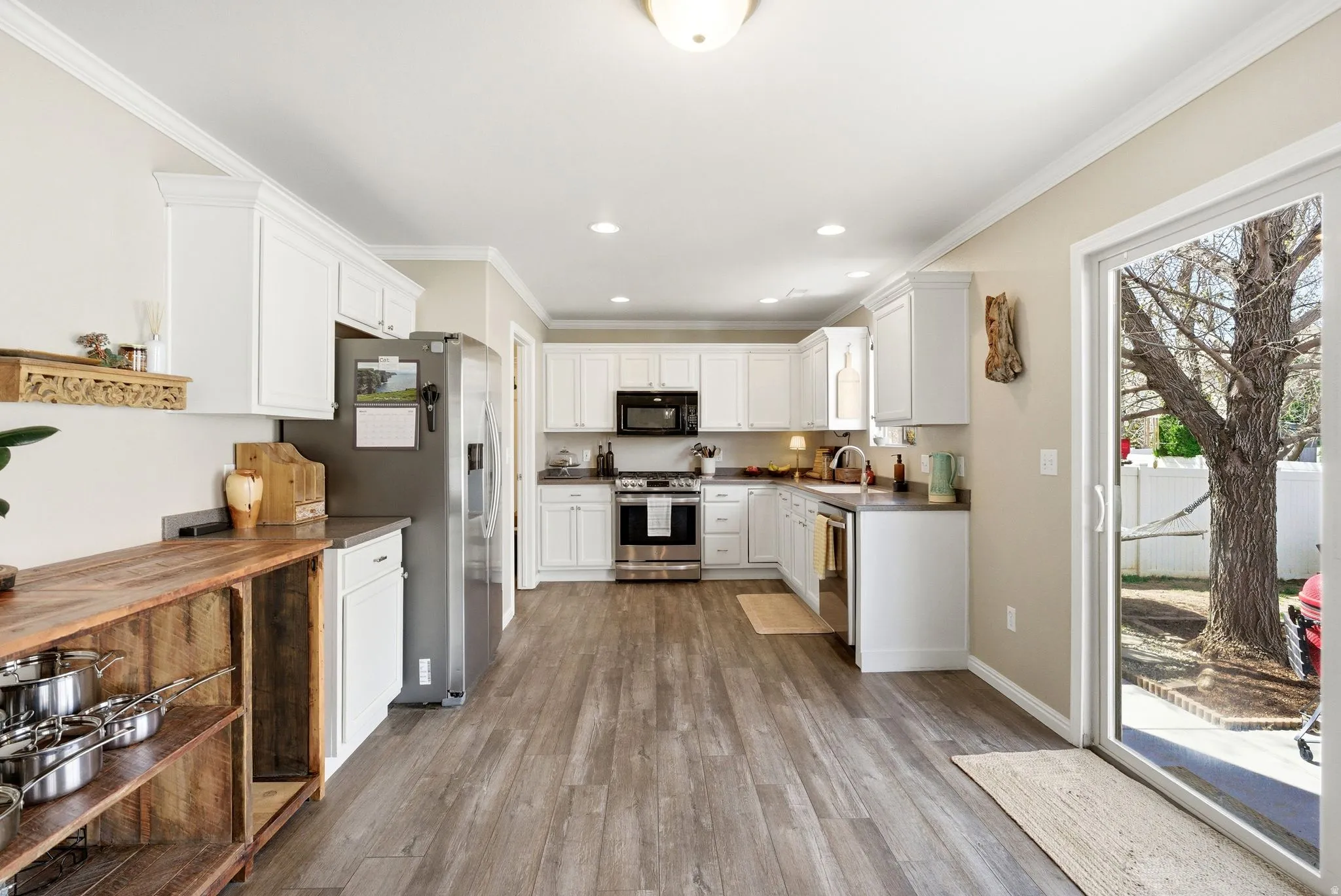 Kitchen featuring stainless steel appliances, white cabinetry, light wood-style flooring, recessed lighting, and crown molding
