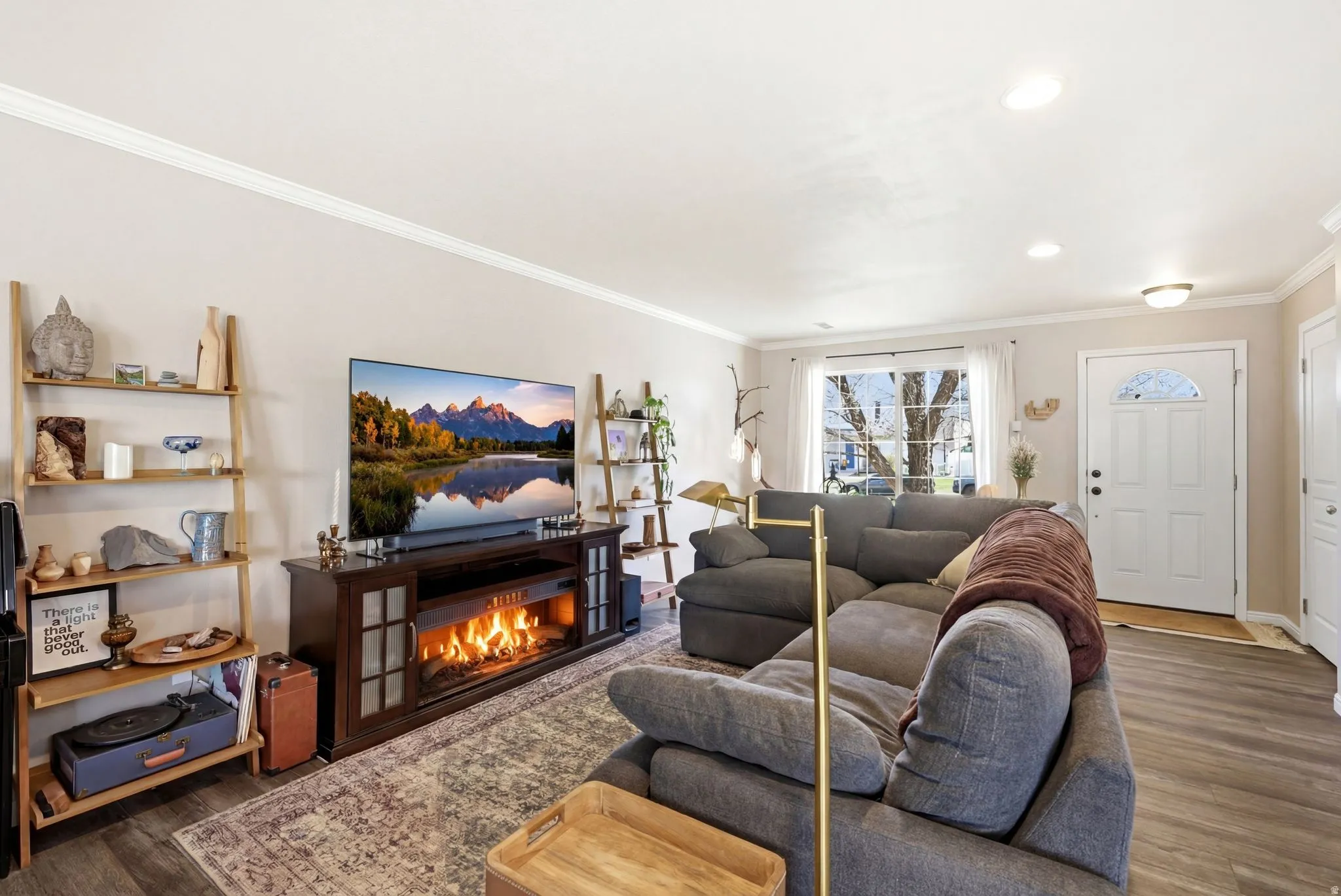 Living room with dark wood-style floors, crown molding, a glass covered fireplace, and recessed lighting
