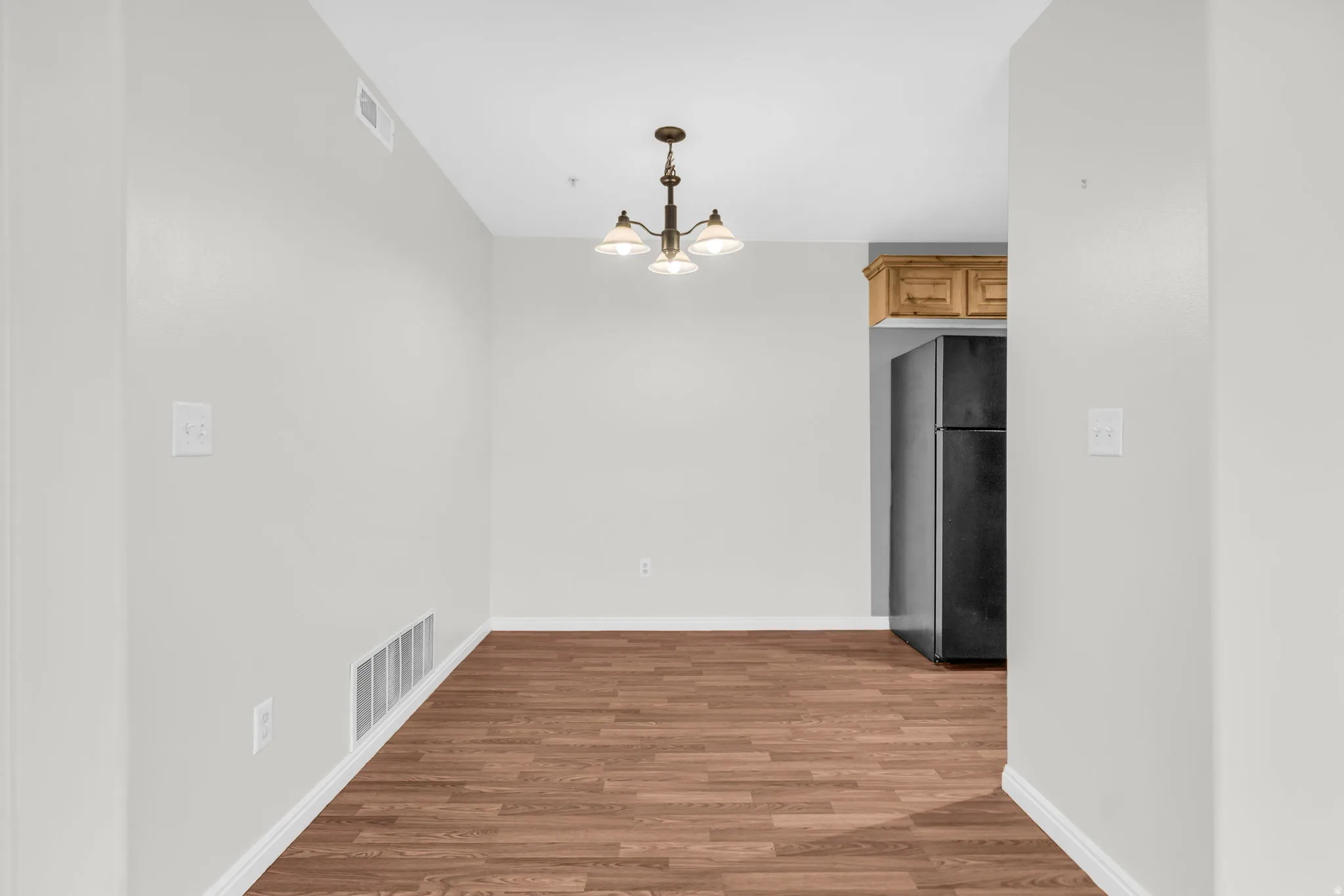 Unfurnished dining area featuring dark wood-style flooring and suspended lighting