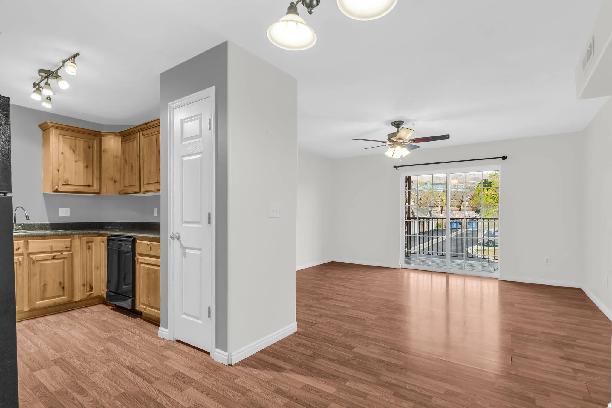 Kitchen with light wood-style flooring, dishwasher, a ceiling fan, wood finish cabinets, and open floor plan