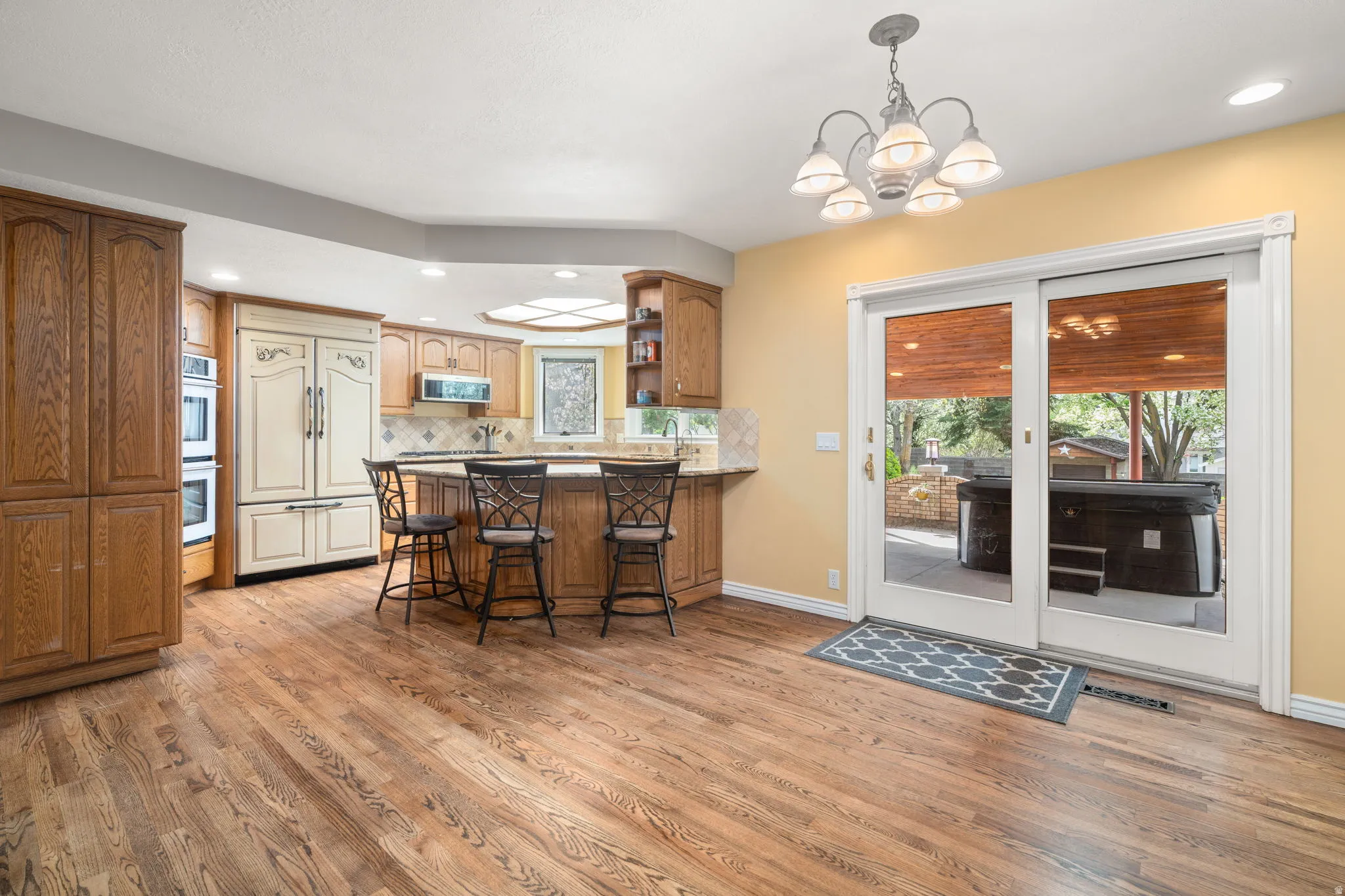 Kitchen featuring a peninsula, a kitchen breakfast bar, open shelves, hanging lights, and wood finish cabinets