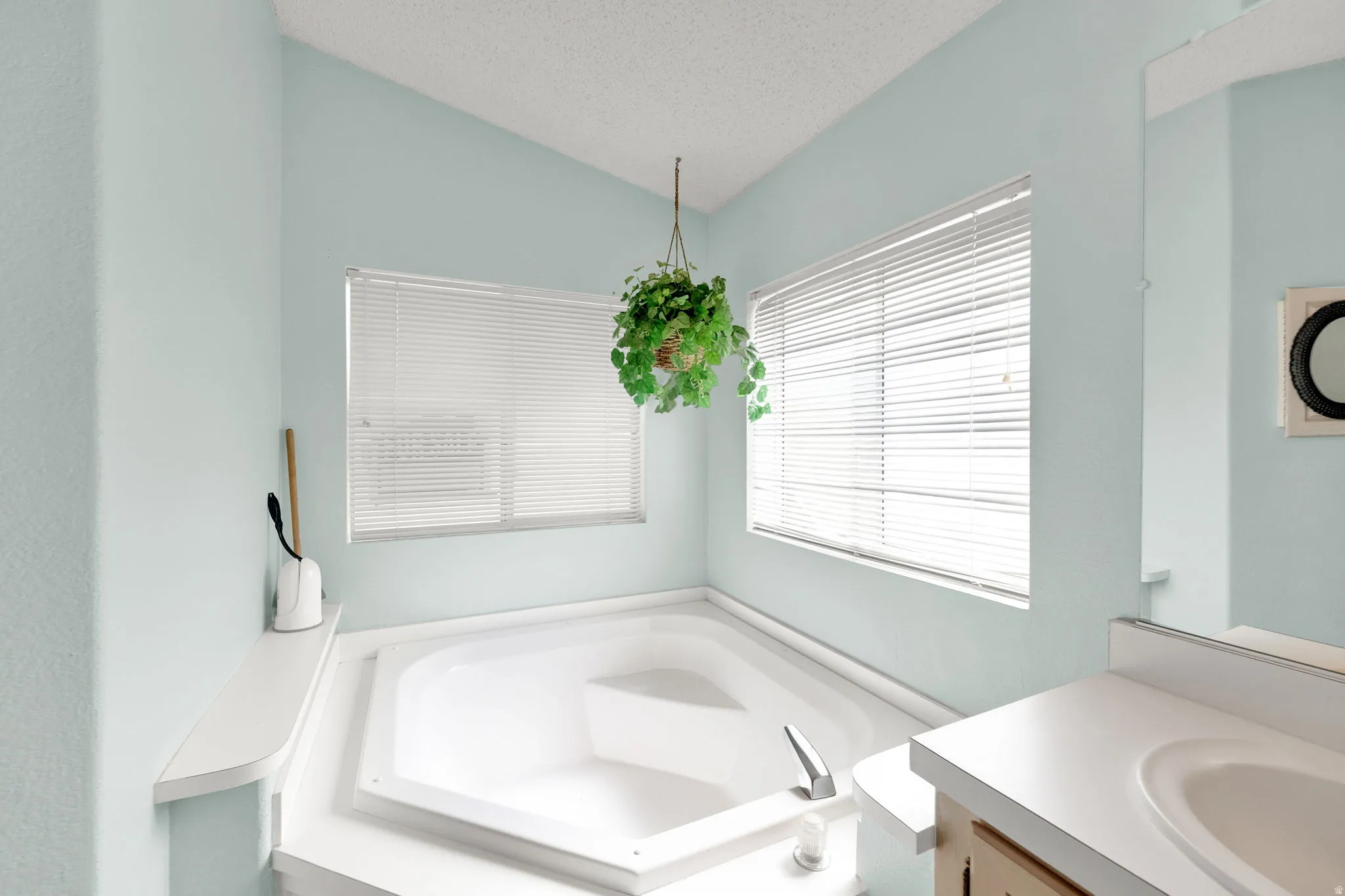 Full bath featuring a garden tub, vanity, and a textured ceiling in primary bathroom