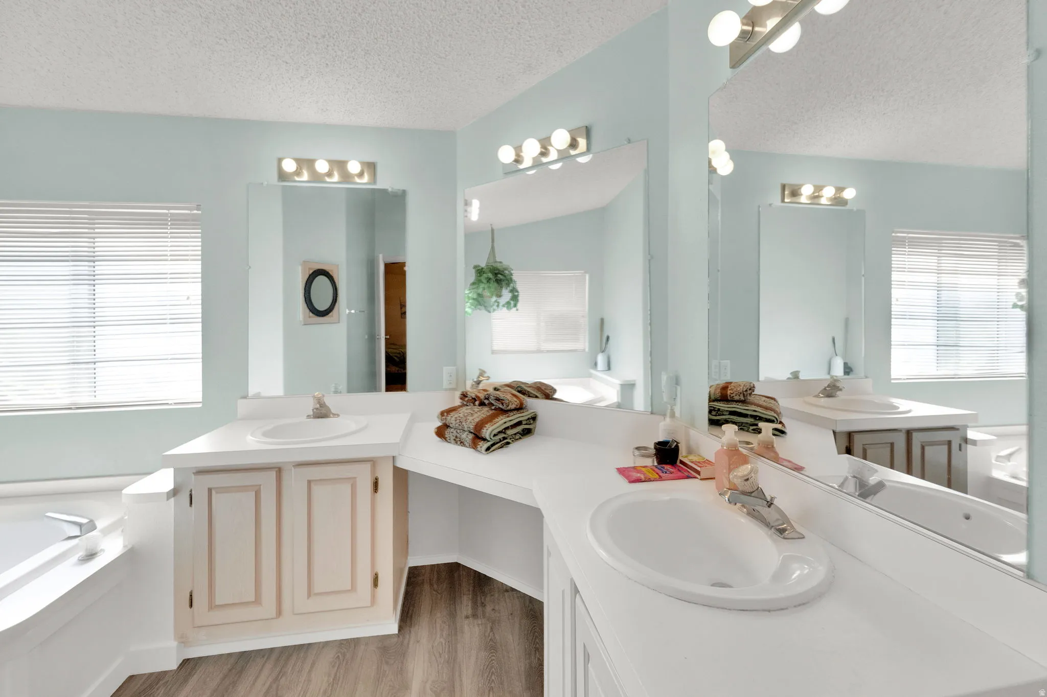Primary Bathroom with double vanity, two vanities, a bath, and light wood-style flooring