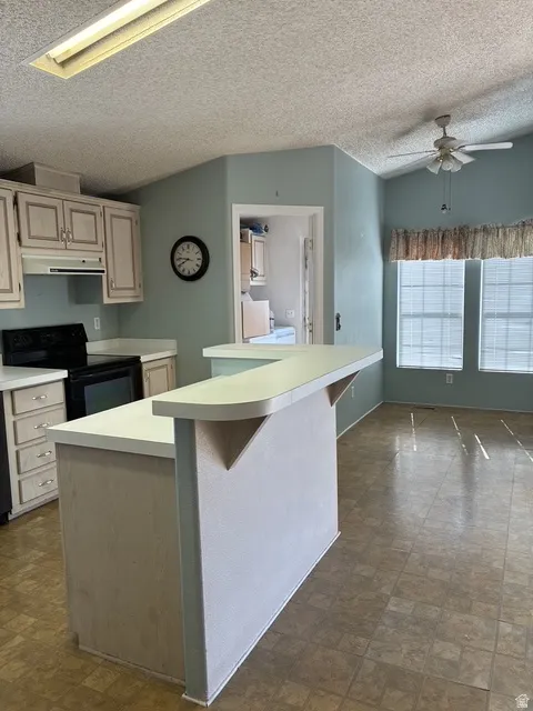Kitchen area featuring vinyl flooring, light cabinetry, a peninsula with a breakfast bar, and a ceiling fan