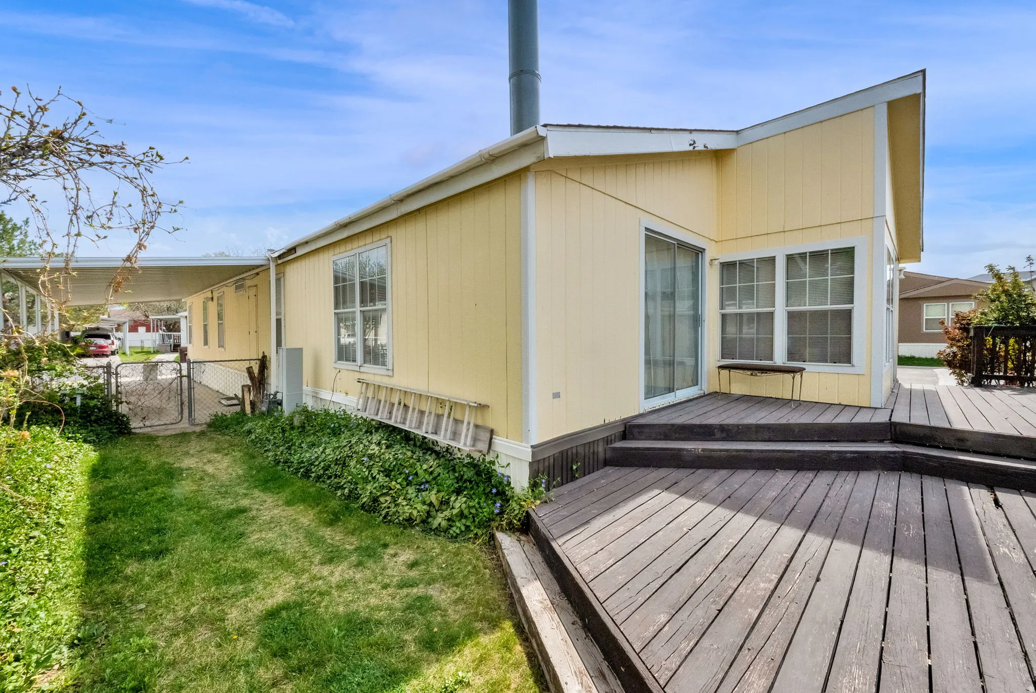 Rear view of house featuring a deck and a gate