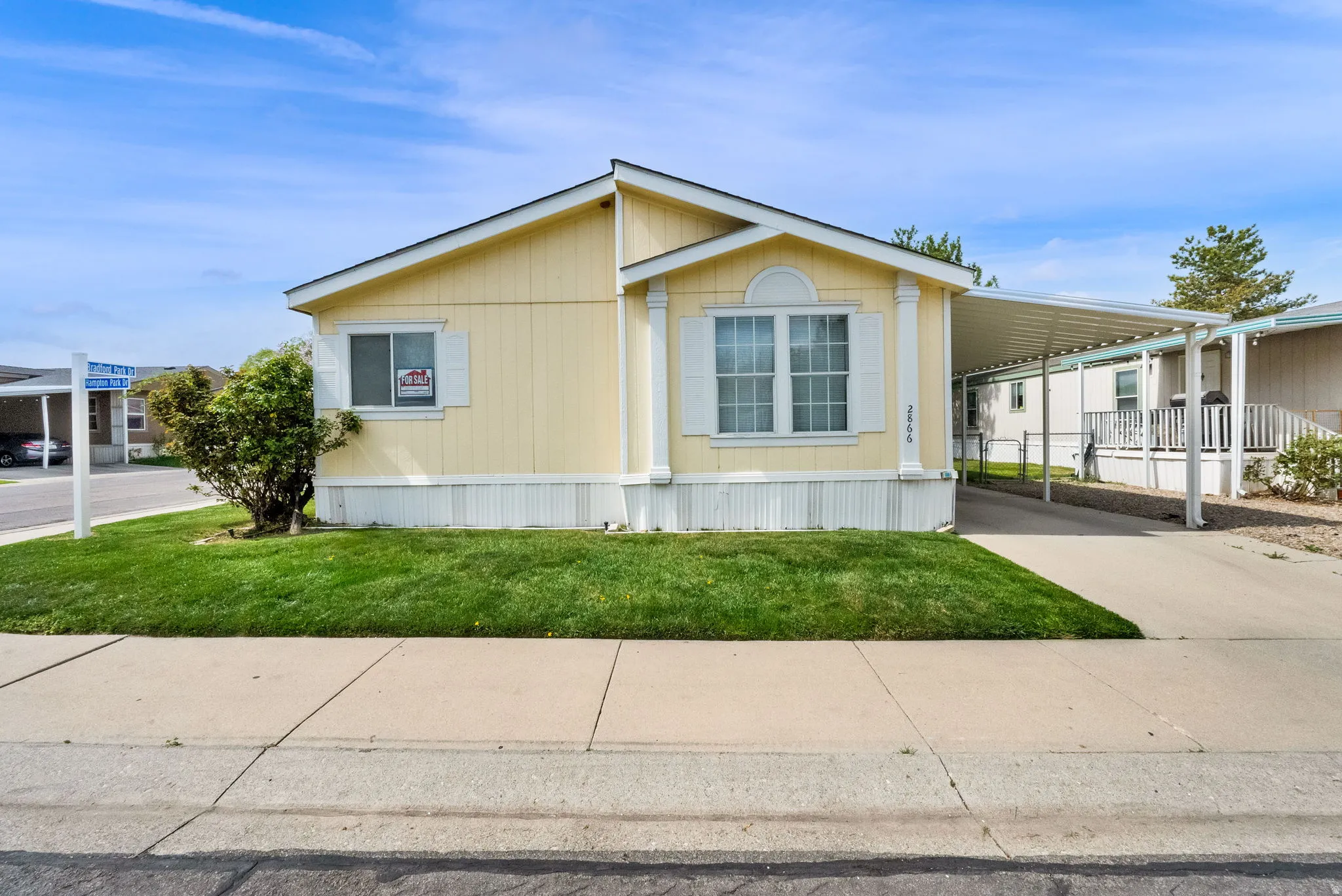 View of front of property featuring a carport, concrete driveway, and a front lawn