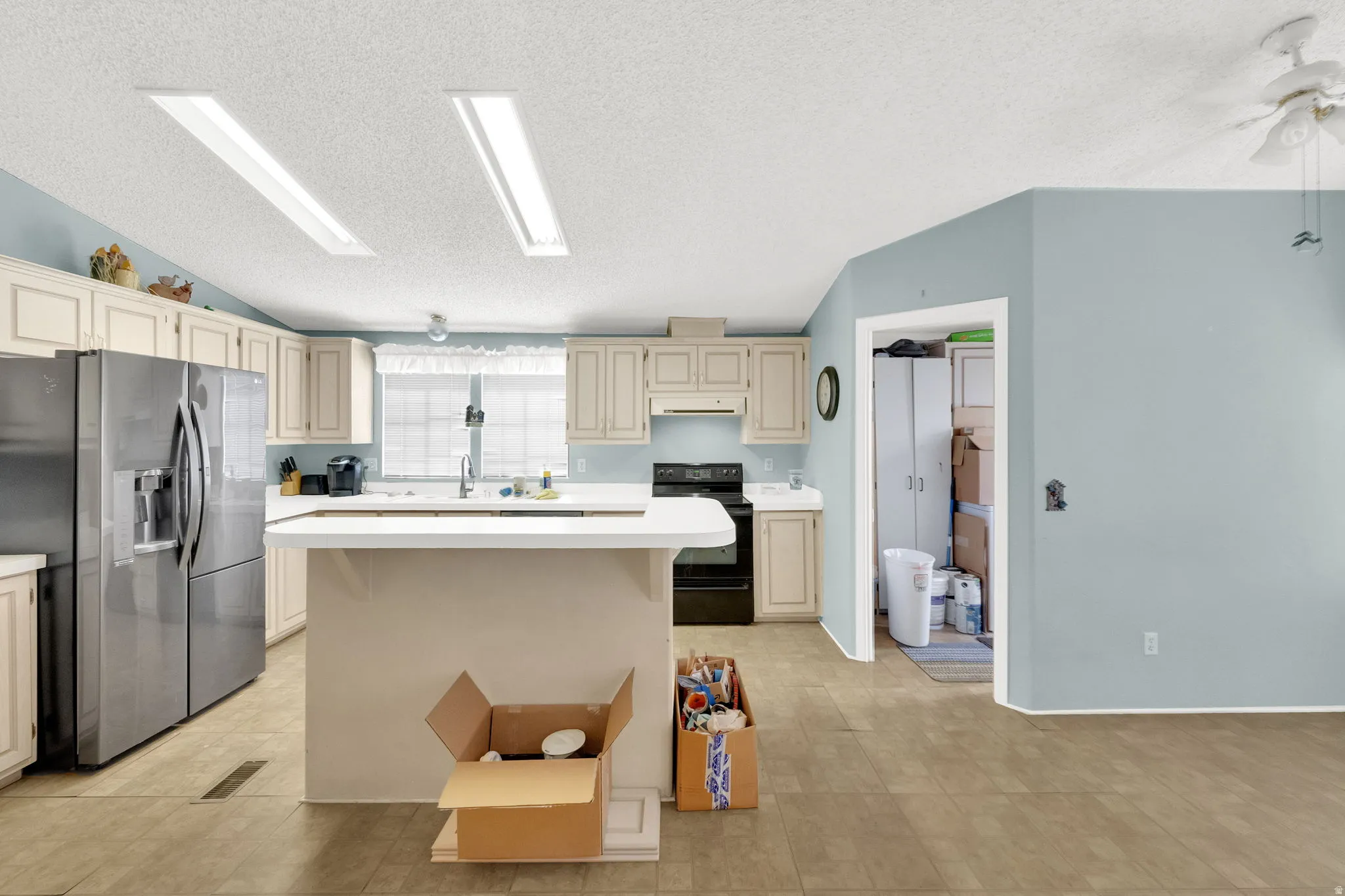 Kitchen with cream cabinetry, light countertops, and stainless steel refrigerator with ice dispenser