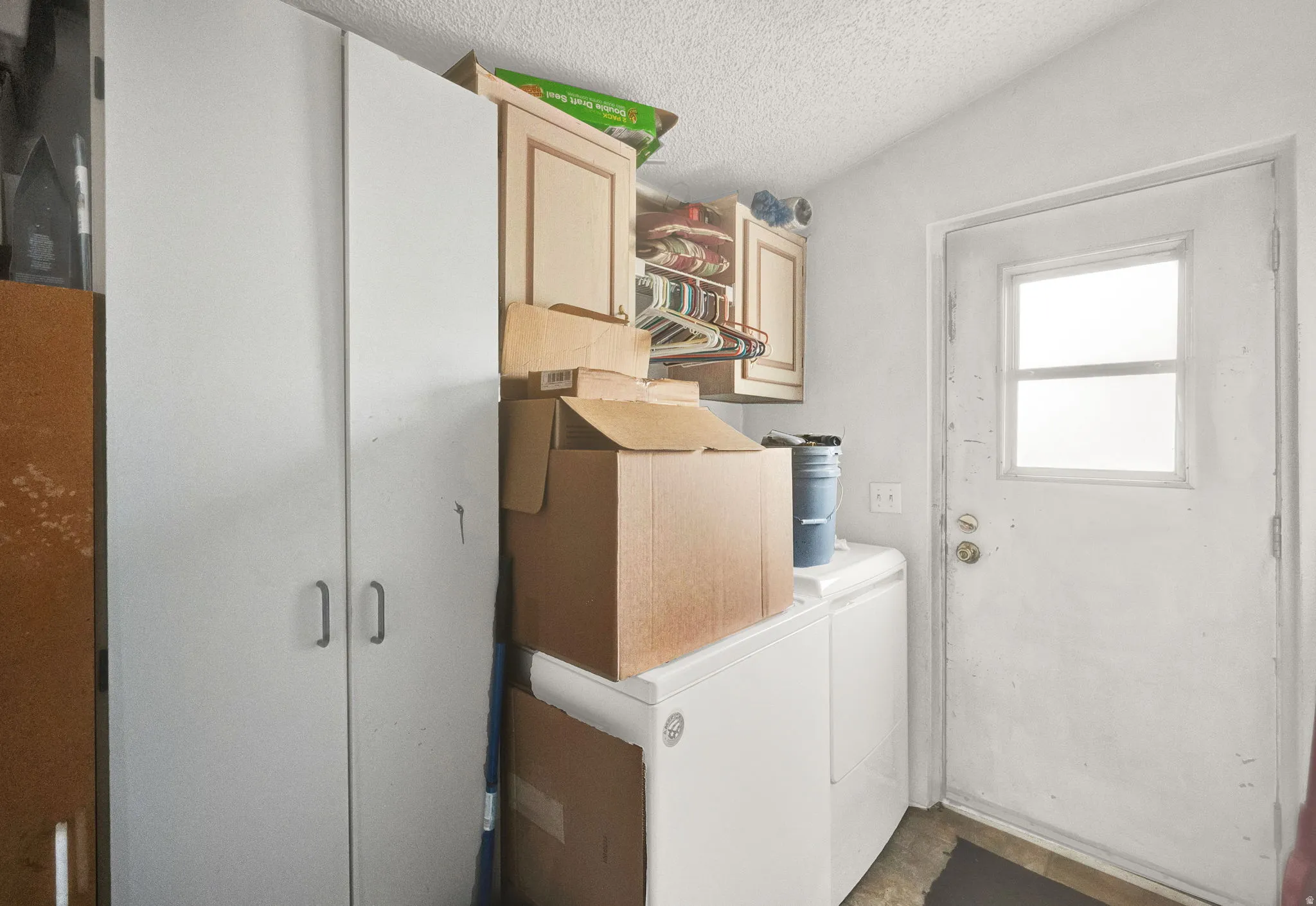 Laundry area featuring a textured ceiling and cabinet space