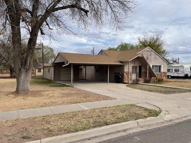 View of front of property with concrete driveway, roof with shingles, an attached carport, an attached garage, and a porch
