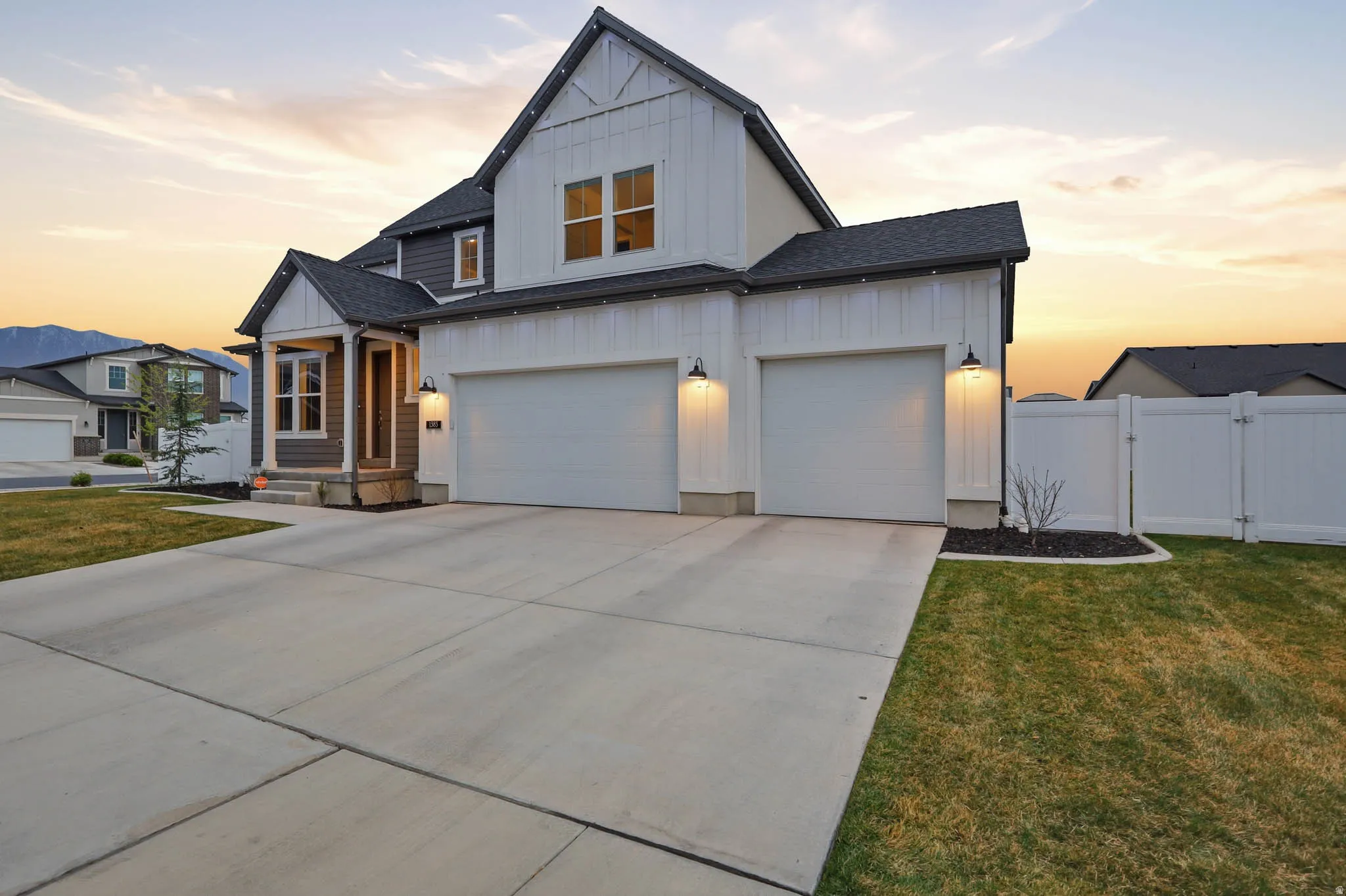 Modern farmhouse style home with board and batten siding, concrete driveway, a gate, a shingled roof, and an attached garage