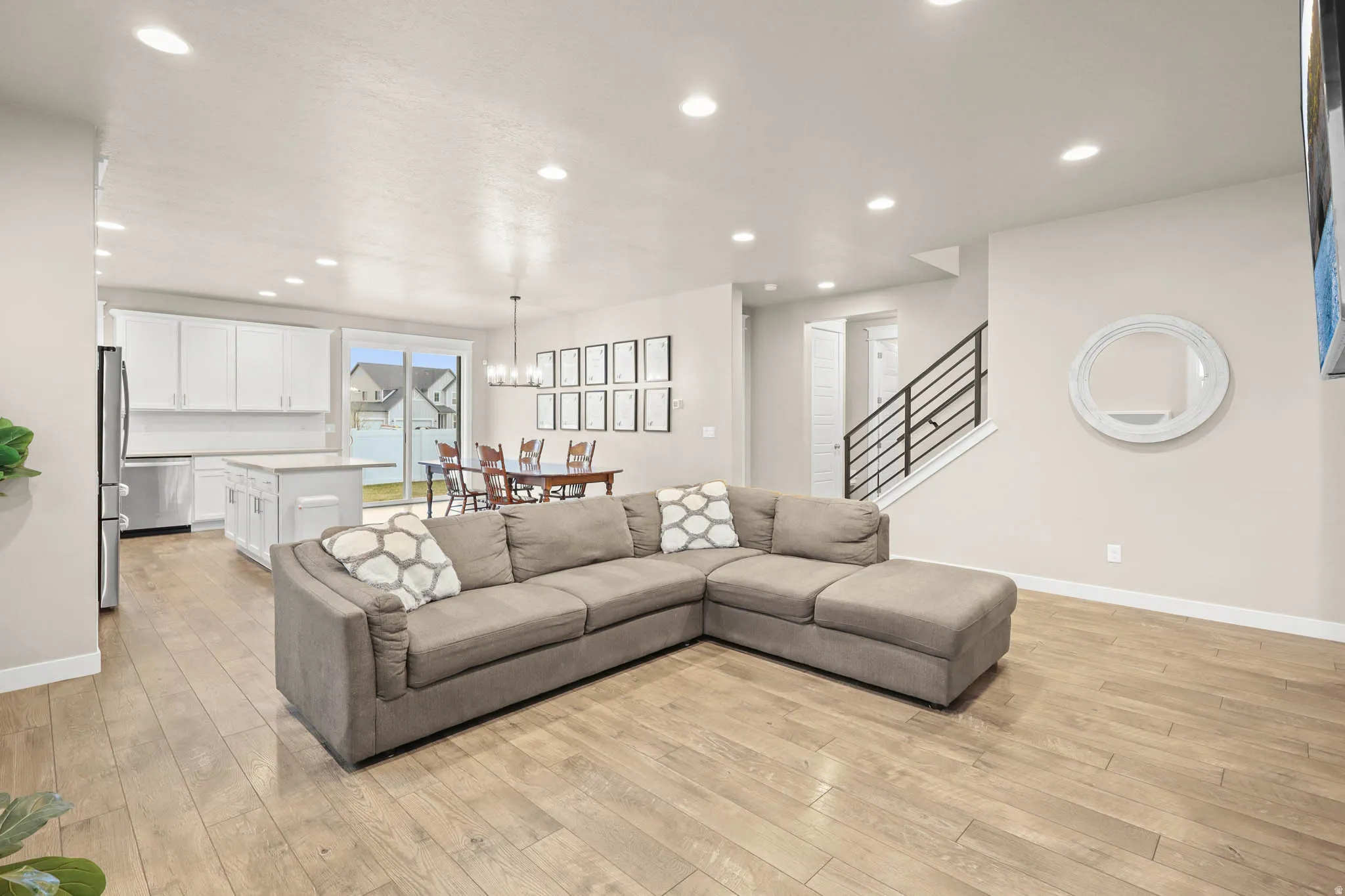 Living room with light LVP flooring and suspended lighting