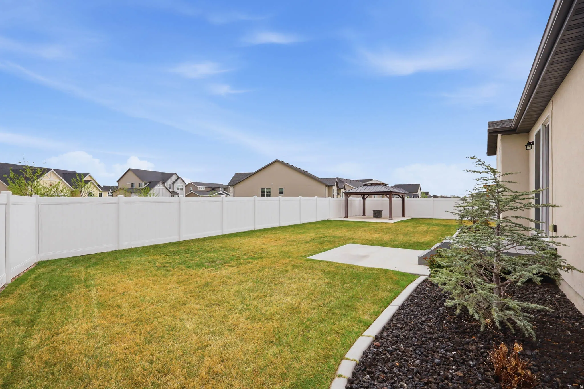 Fenced backyard with a patio, a gazebo, and a residential view