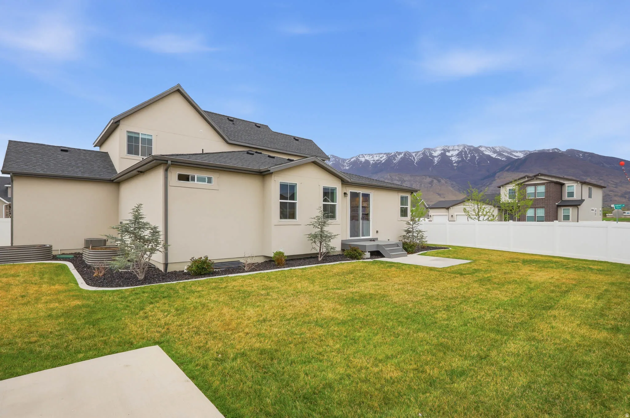 Back of property featuring stucco siding, a mountain view, and roof with shingles