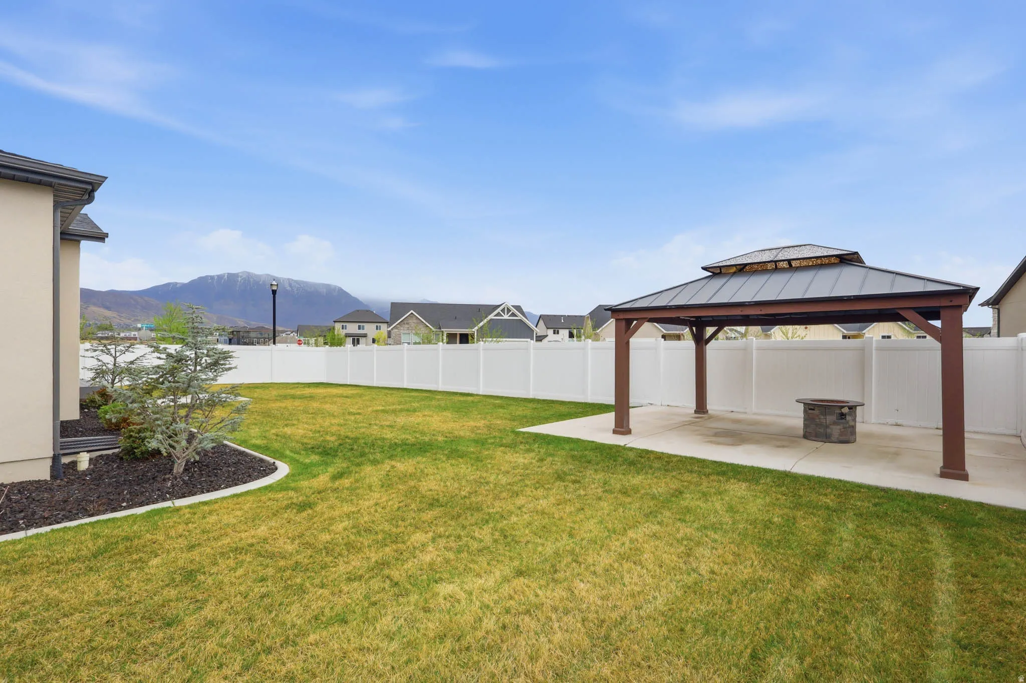 Fenced backyard with a mountain view, a patio, and a gazebo