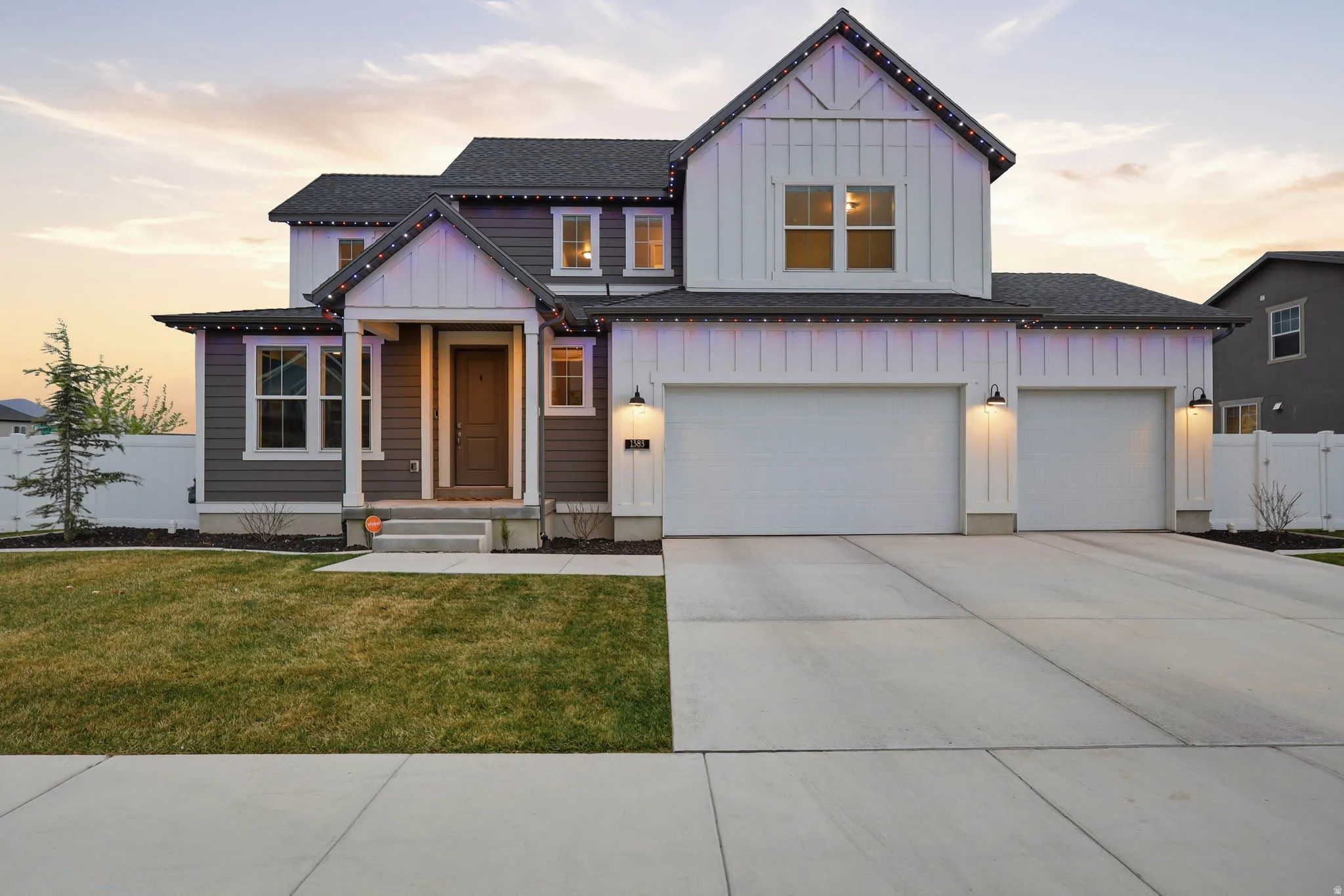 Modern farmhouse with board and batten siding, a shingled roof, and concrete driveway