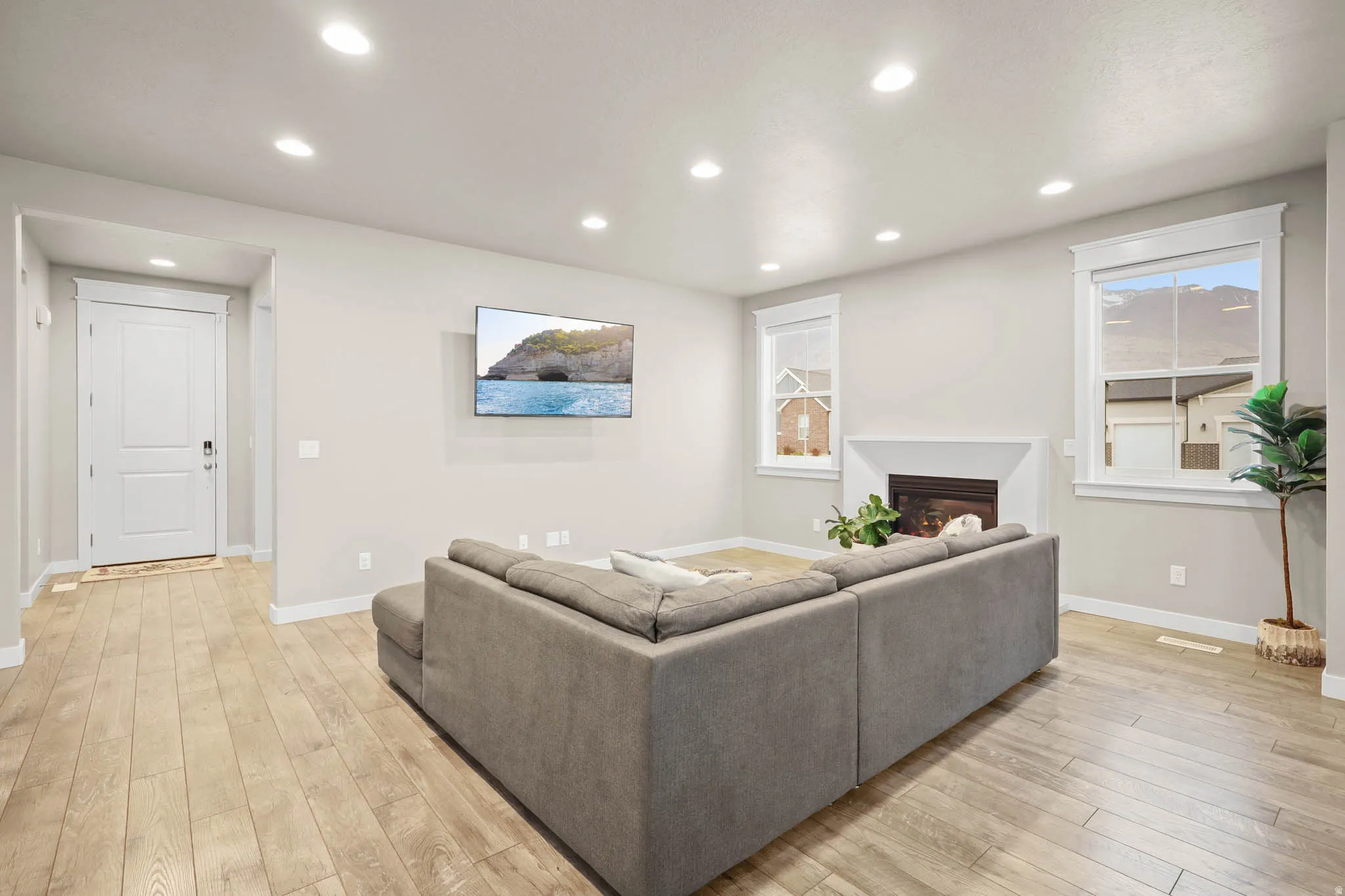 Living room featuring light wood finished floors, recessed lighting, and a glass-covered fireplace