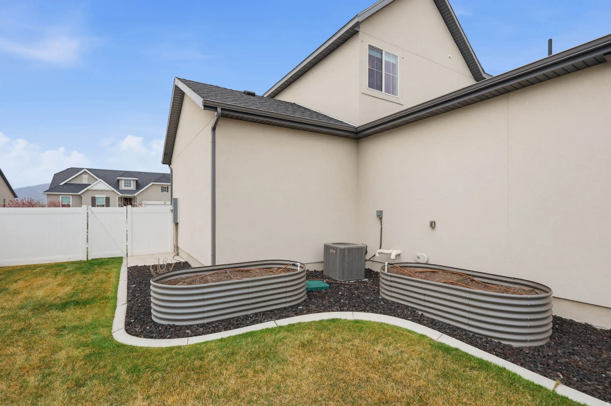 Exterior view of stucco siding, a downspout, a gate, and gutters