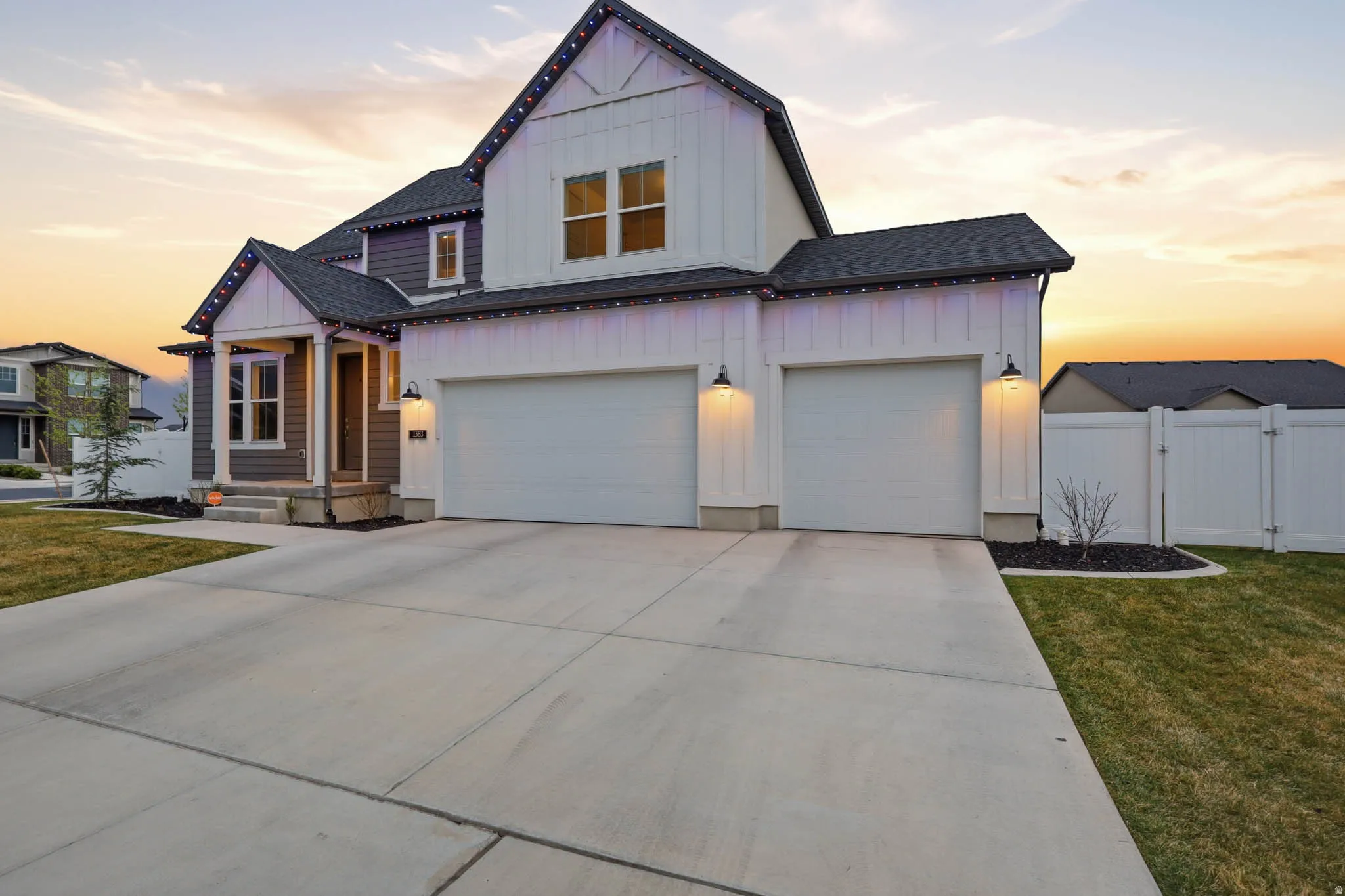 Modern farmhouse with board and batten siding, concrete driveway, a shingled roof, and a gate