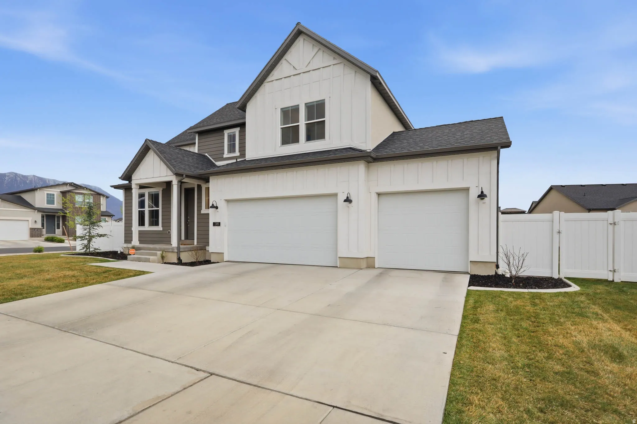 Modern farmhouse style home featuring board and batten siding, concrete driveway, a shingled roof, a gate, and a garage