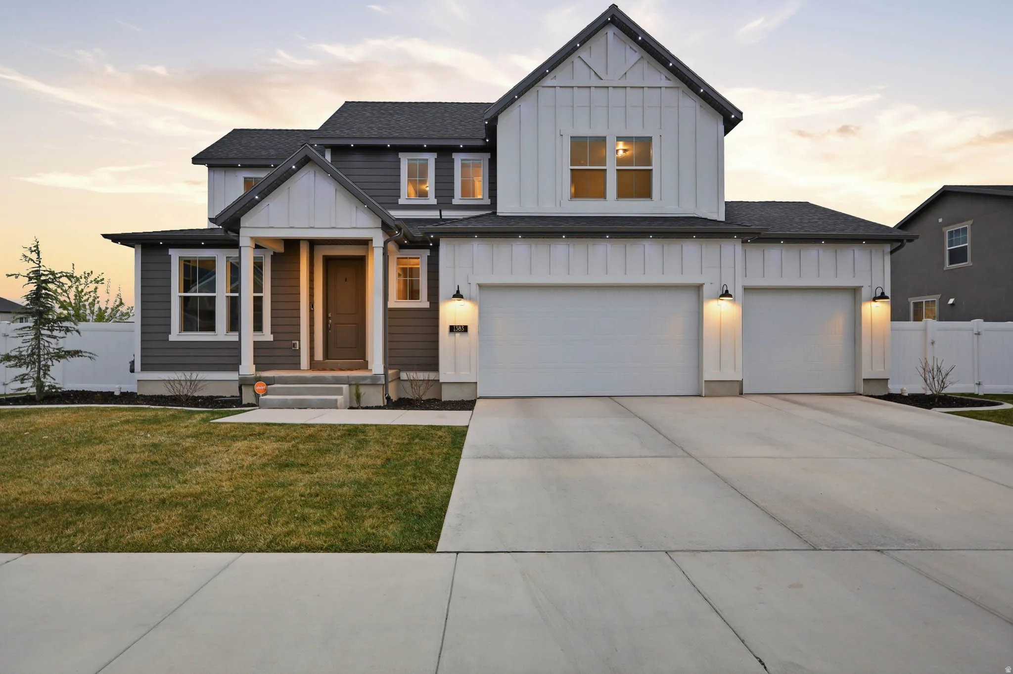 Modern farmhouse with board and batten siding, a shingled roof, driveway, and a garage