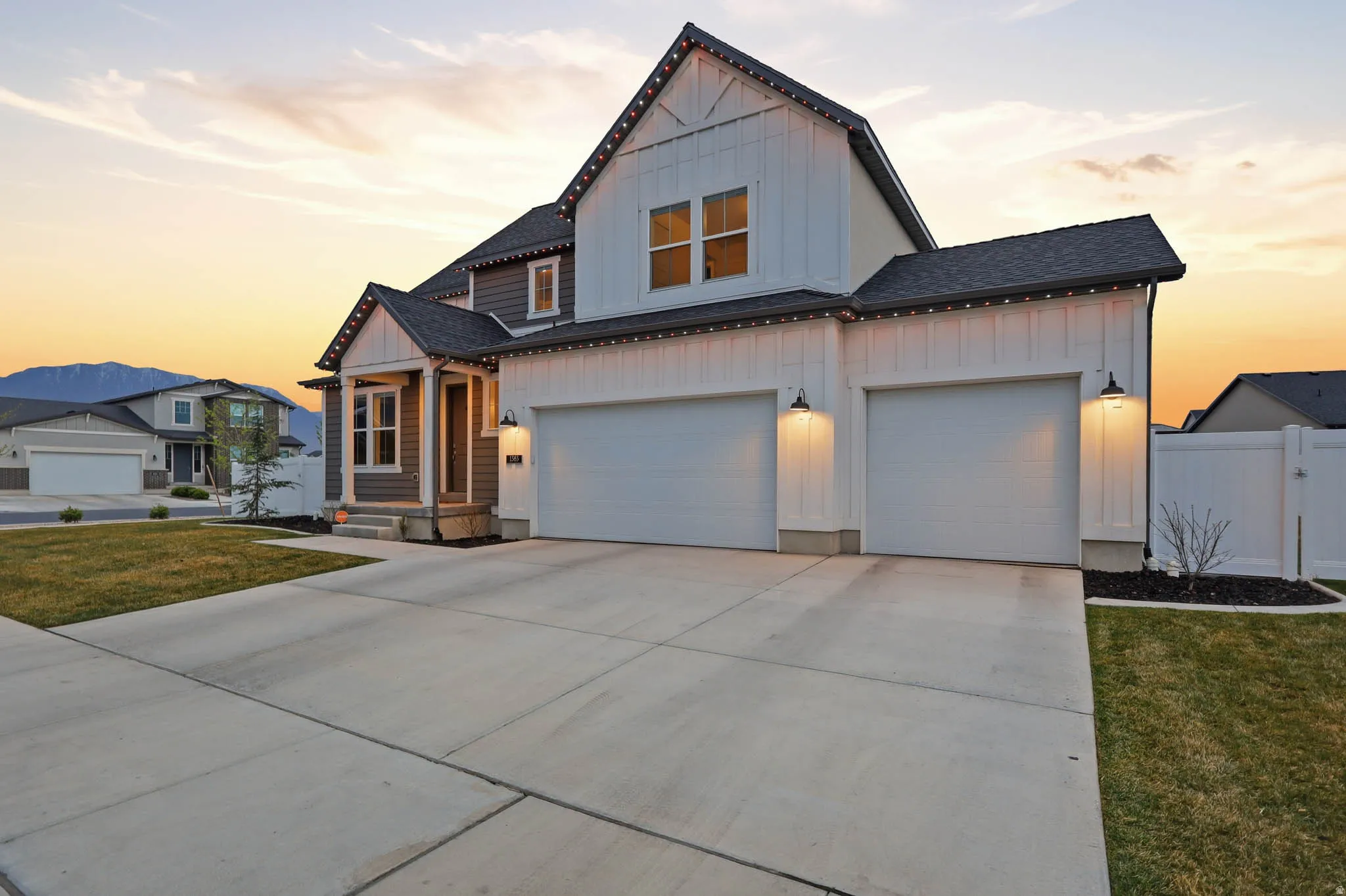 Modern farmhouse featuring board and batten siding, concrete driveway, a gate, a shingled roof, and a garage