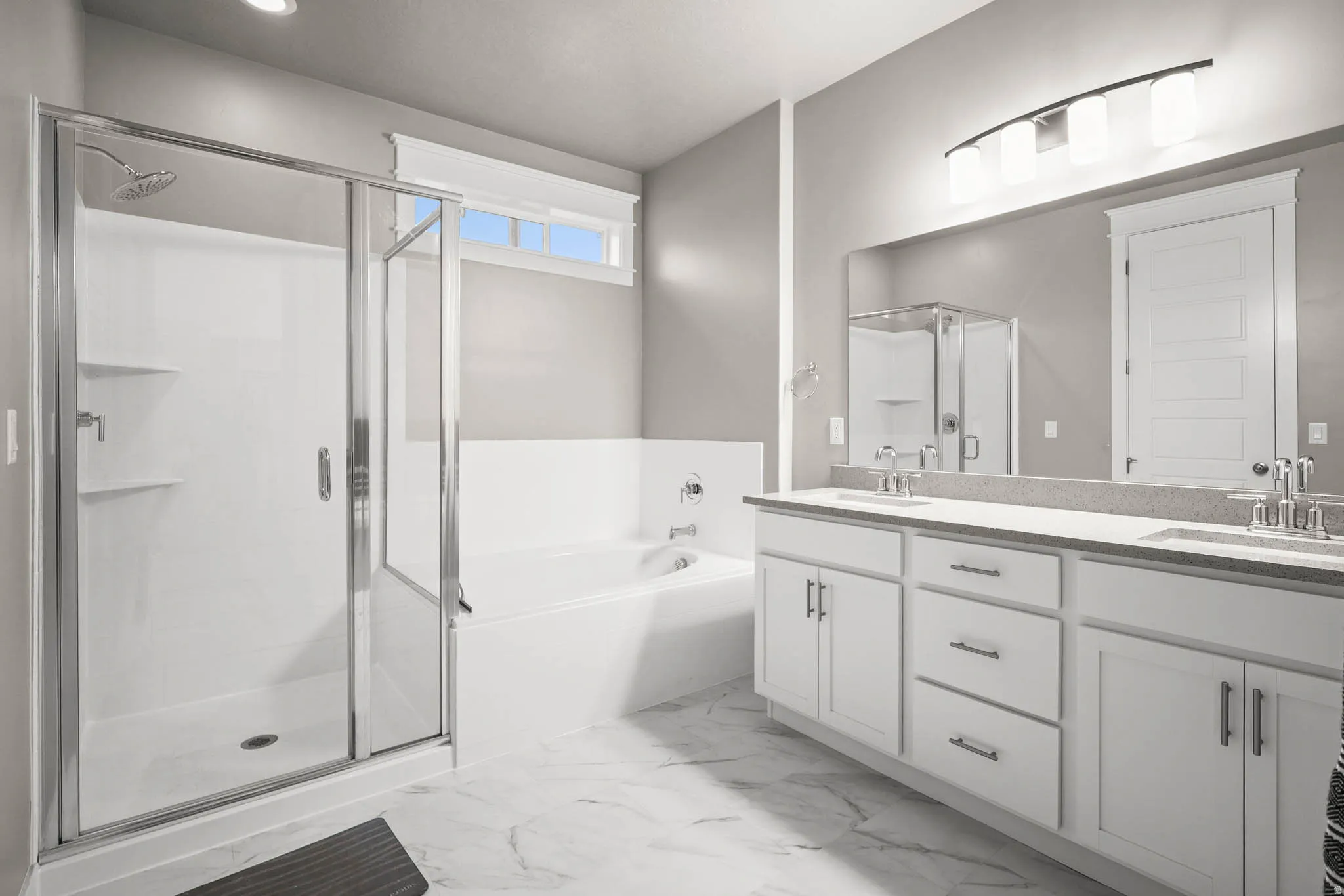 Primary Full bath with double vanity, a shower stall, a bath, and light marble finish floors