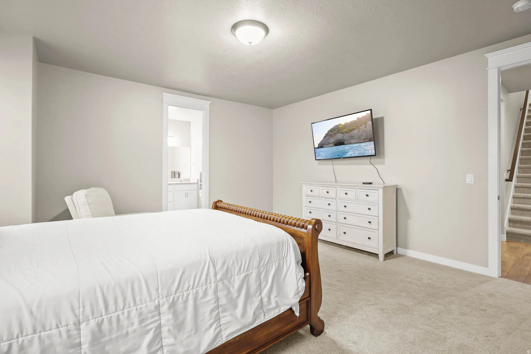 Primary Bedroom with carpet floors, ensuite bath, and a textured ceiling