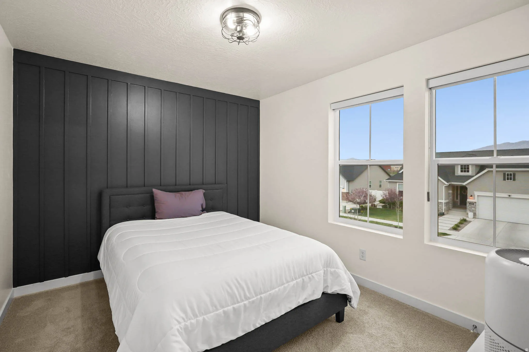 Bedroom featuring light carpet, a textured ceiling, and an accent wall