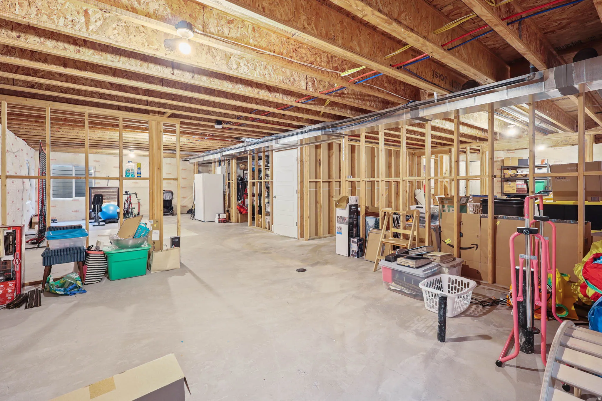 Unfinished below grade area featuring freestanding refrigerator