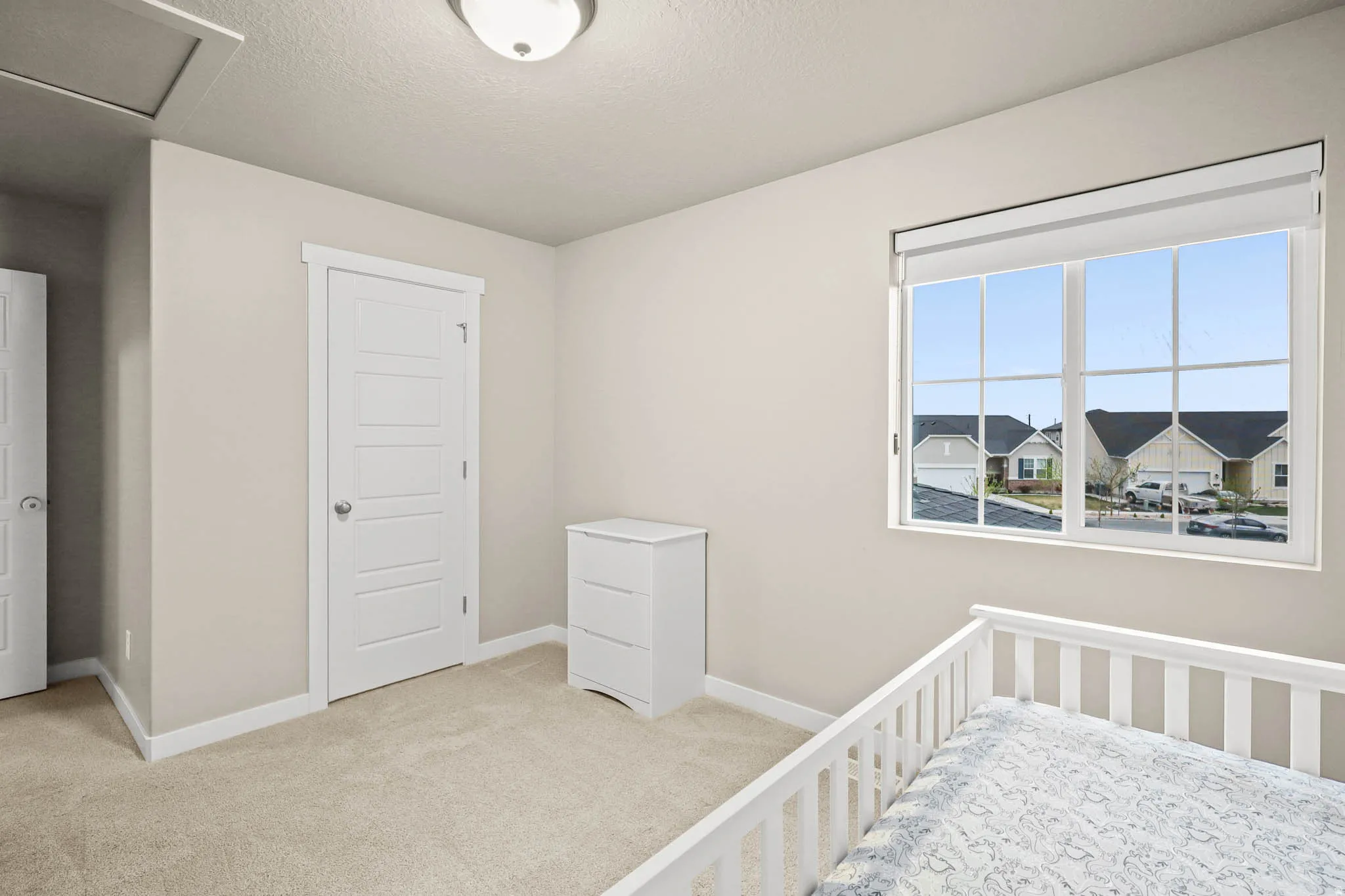 Bedroom featuring light carpet, a textured ceiling, a closet, and a nursery area