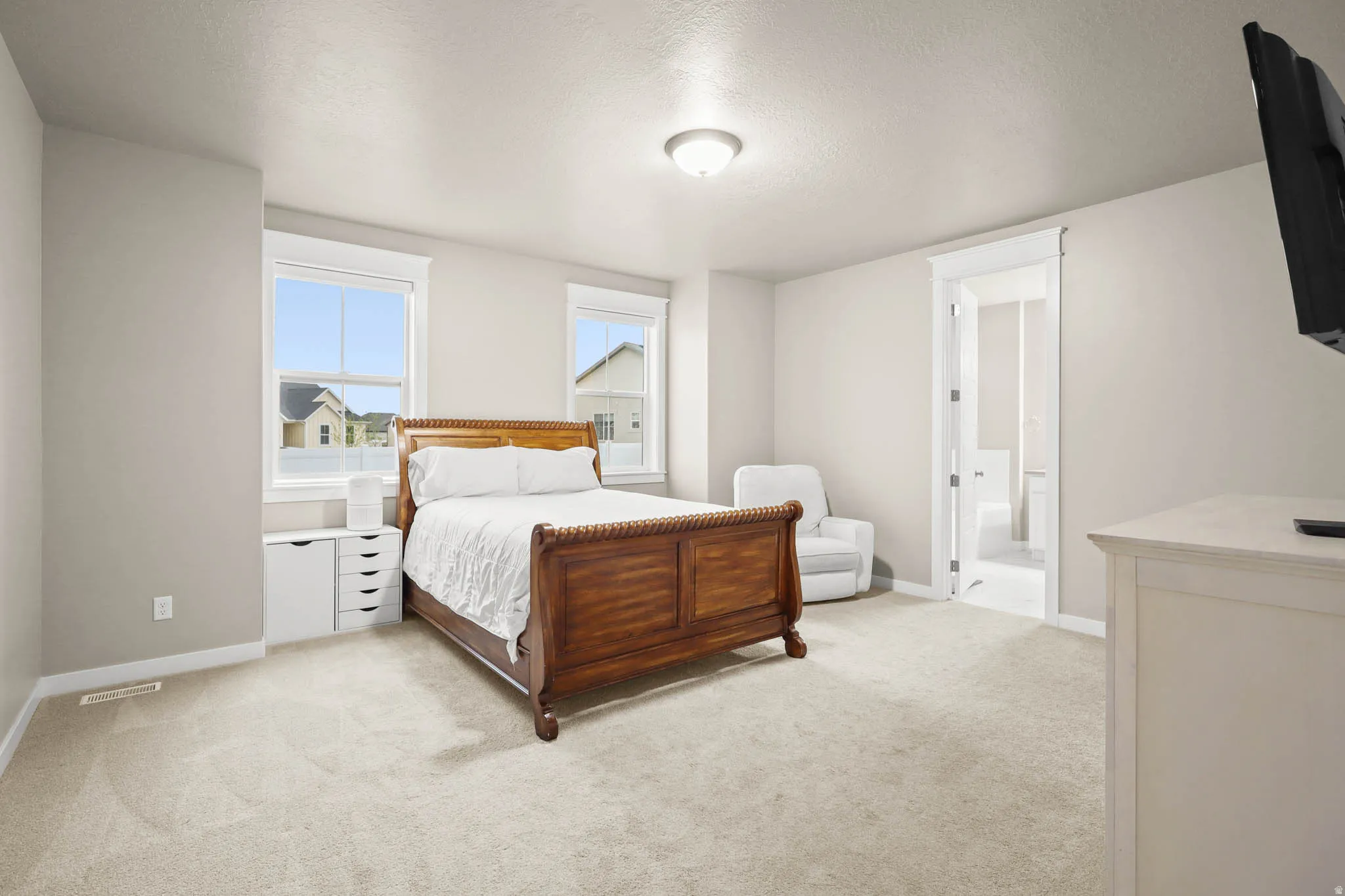Primary Bedroom featuring light colored carpet, a textured ceiling, and a connected bathroom